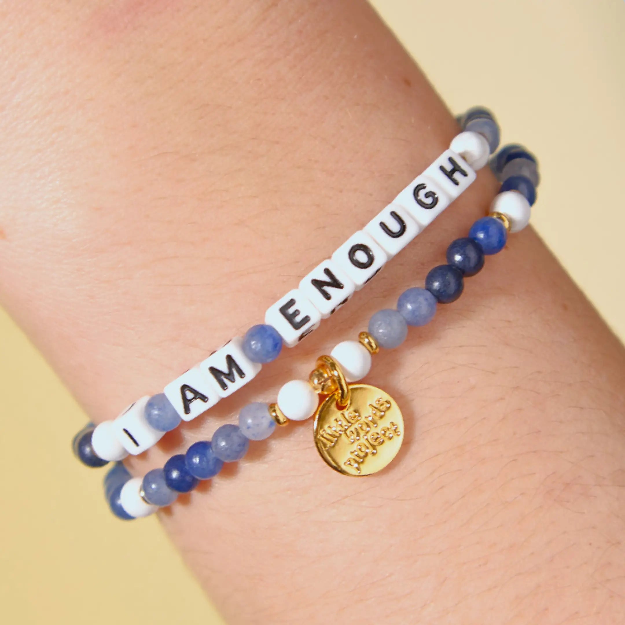 Bracelet with motivational message on a wrist against a yellow background