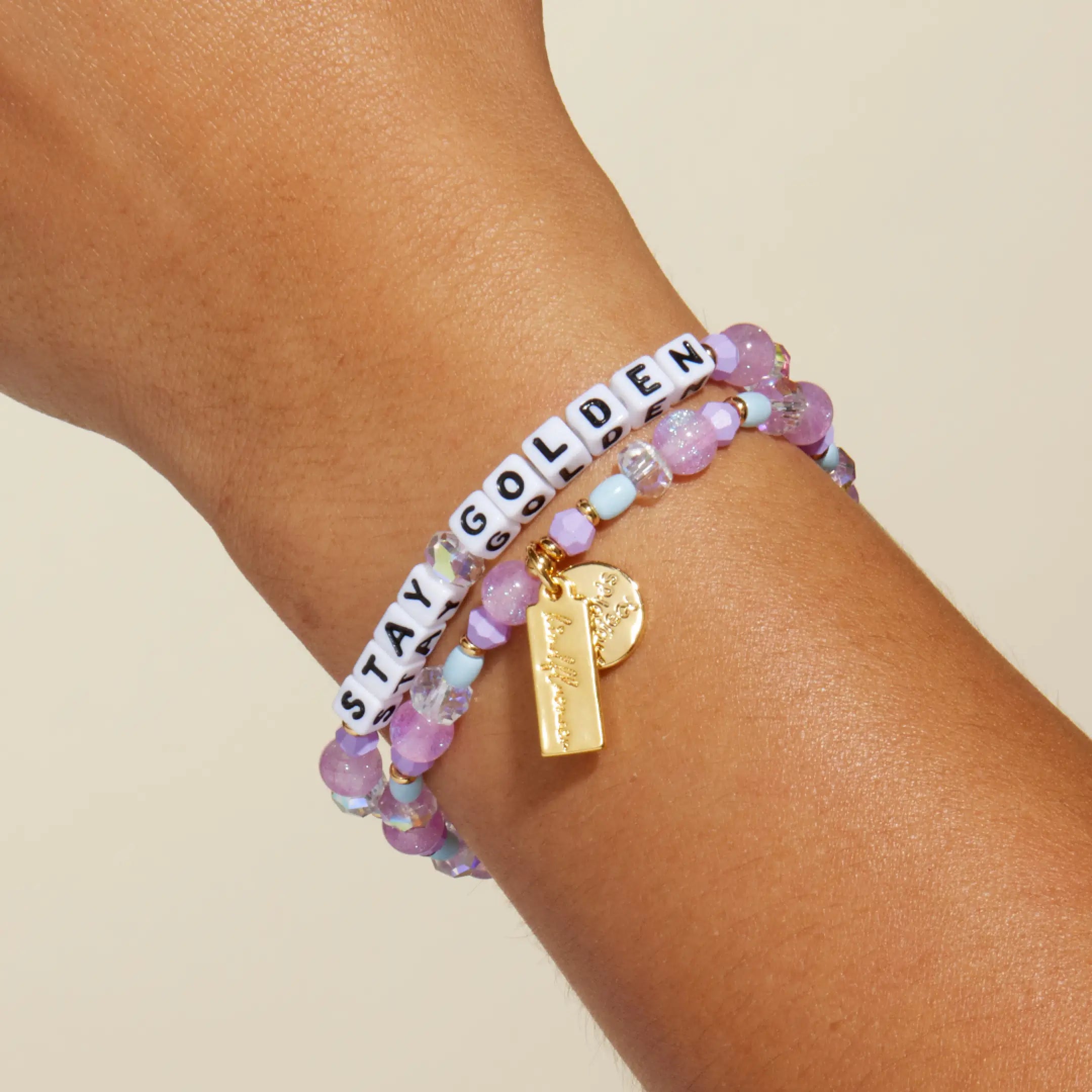 Stay Golden Rylee Ta bracelet with white letter beads and lavender crystal beads worn on a wrist, on-model close up