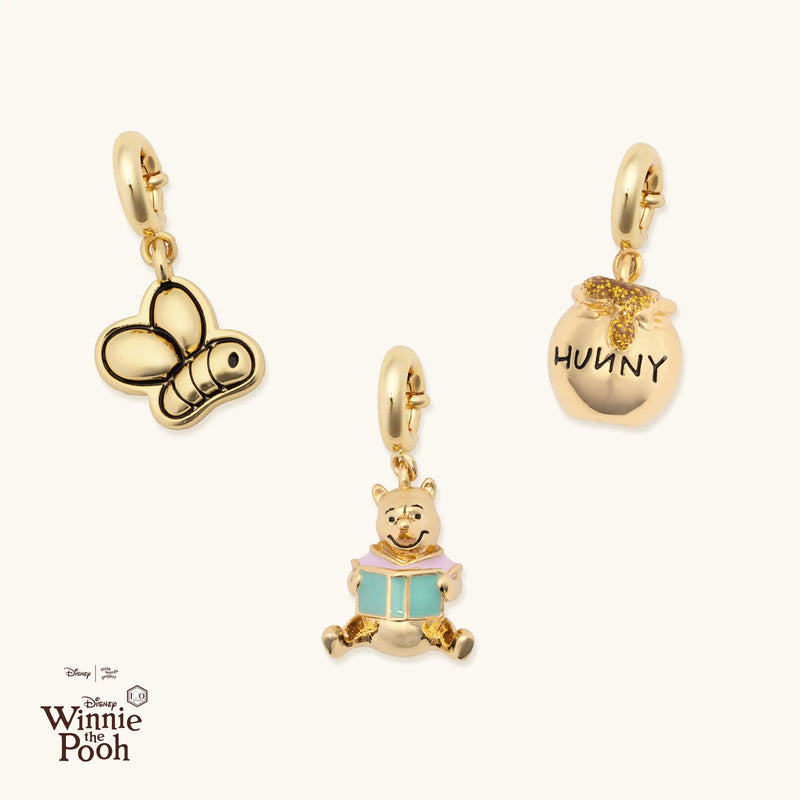 Gold charms inspired by Winnie the Pooh on a white background