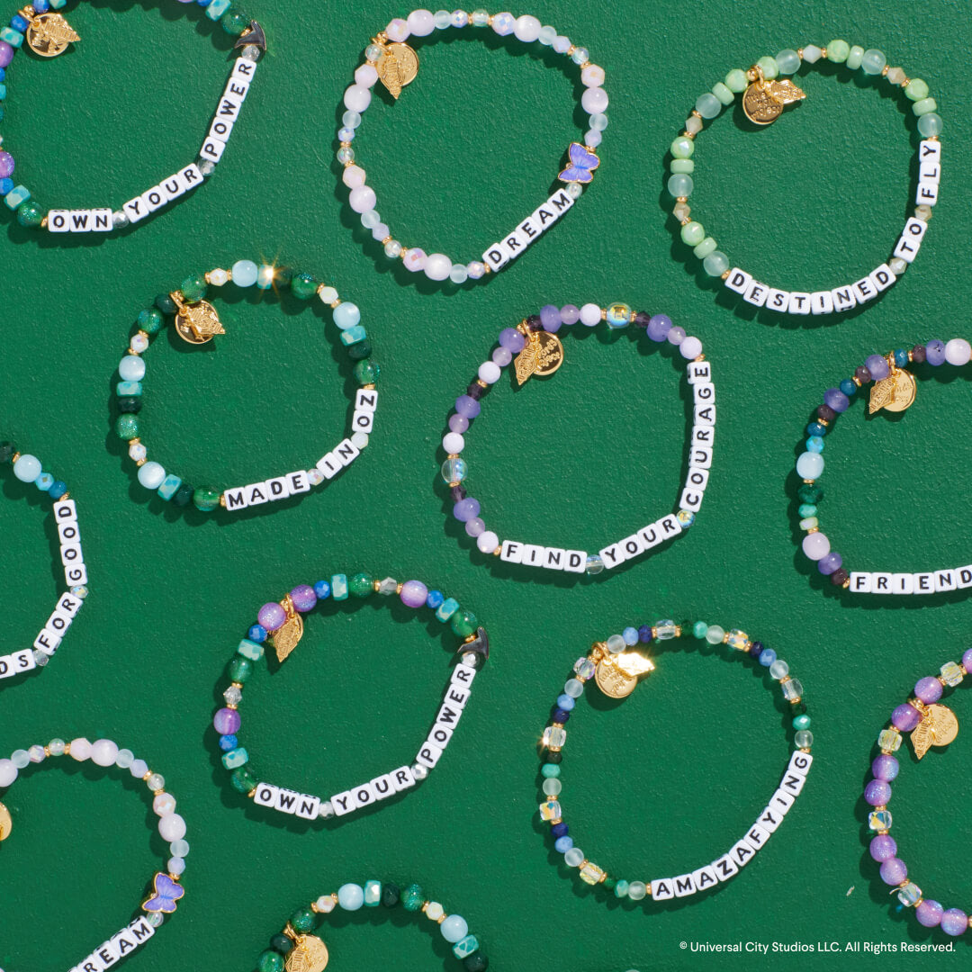 Multiple beaded bracelets with motivational phrases on a green background