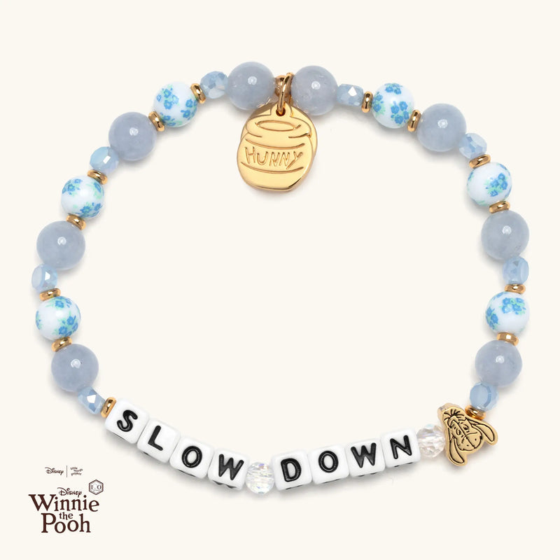 Bracelet with 'SLOW DOWN' and a Hunny Pot tag on a white background