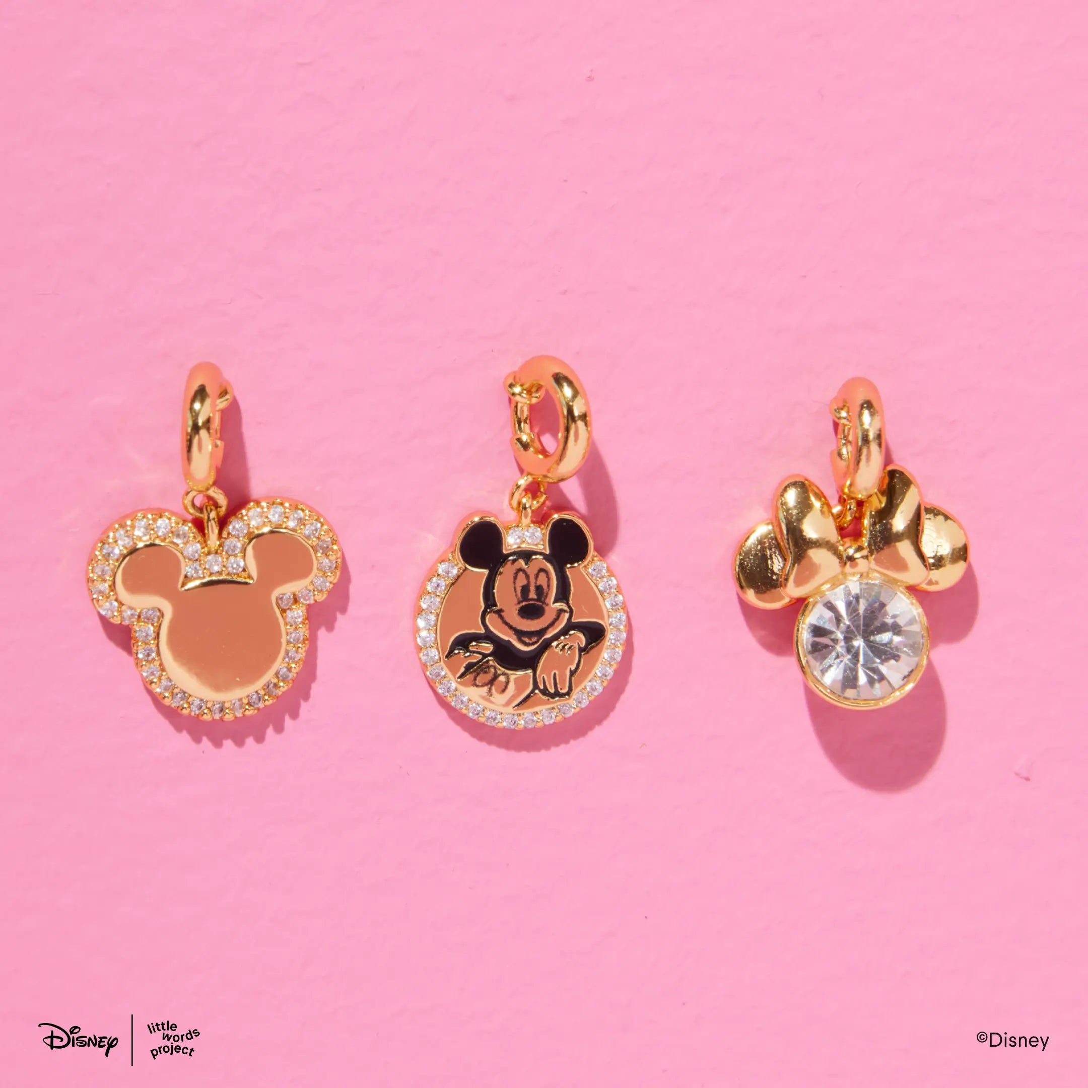 Magic Three Charm Set from Disney Mickey and Friends on pink, three gold plated charms including the Mickey Mouse silhouette, Mickey Mouse badge and Minnie Mouse crystal charms