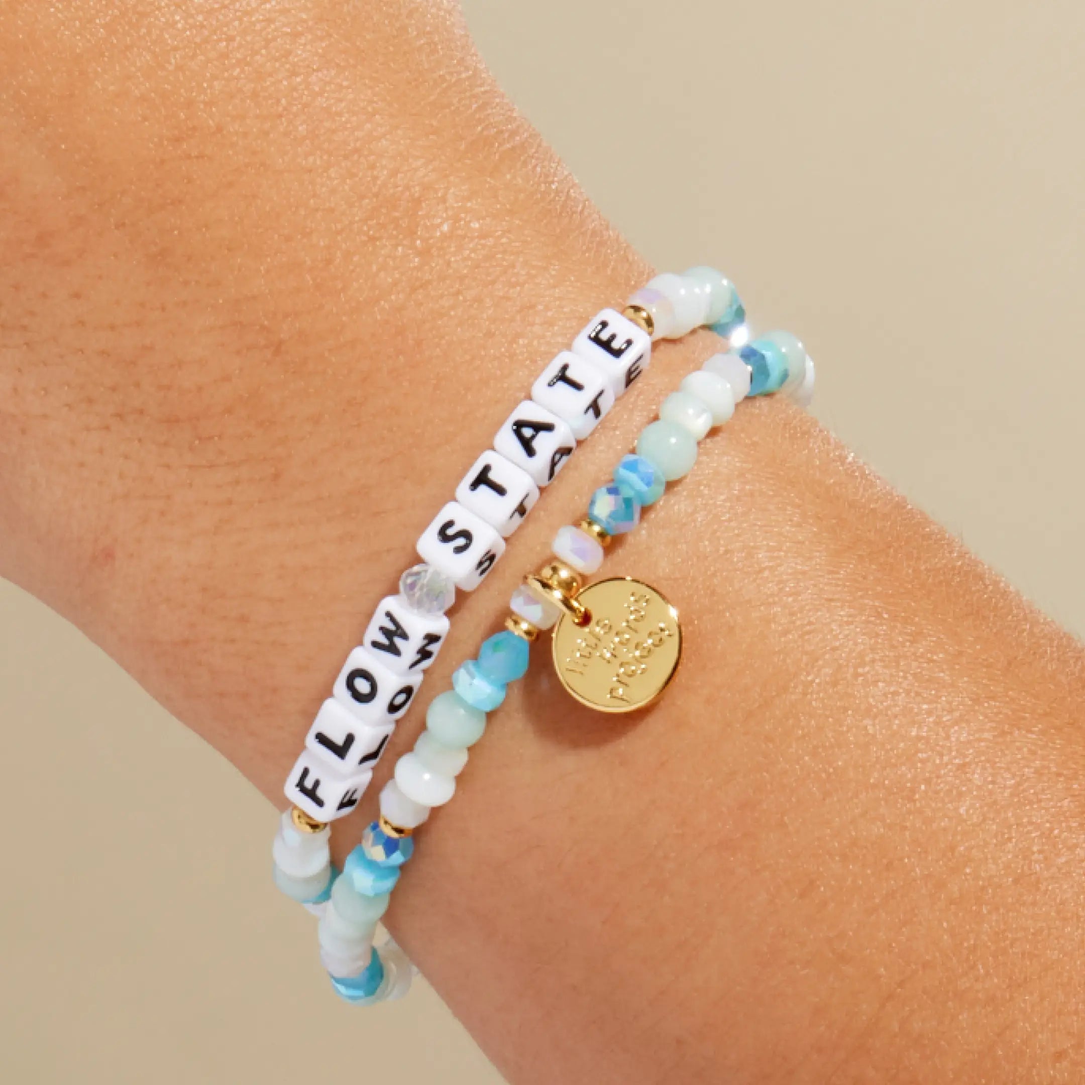 Flow State — on-model wrist shot of beaded word bracelet stacked with other bracelets in blue and neutral beads