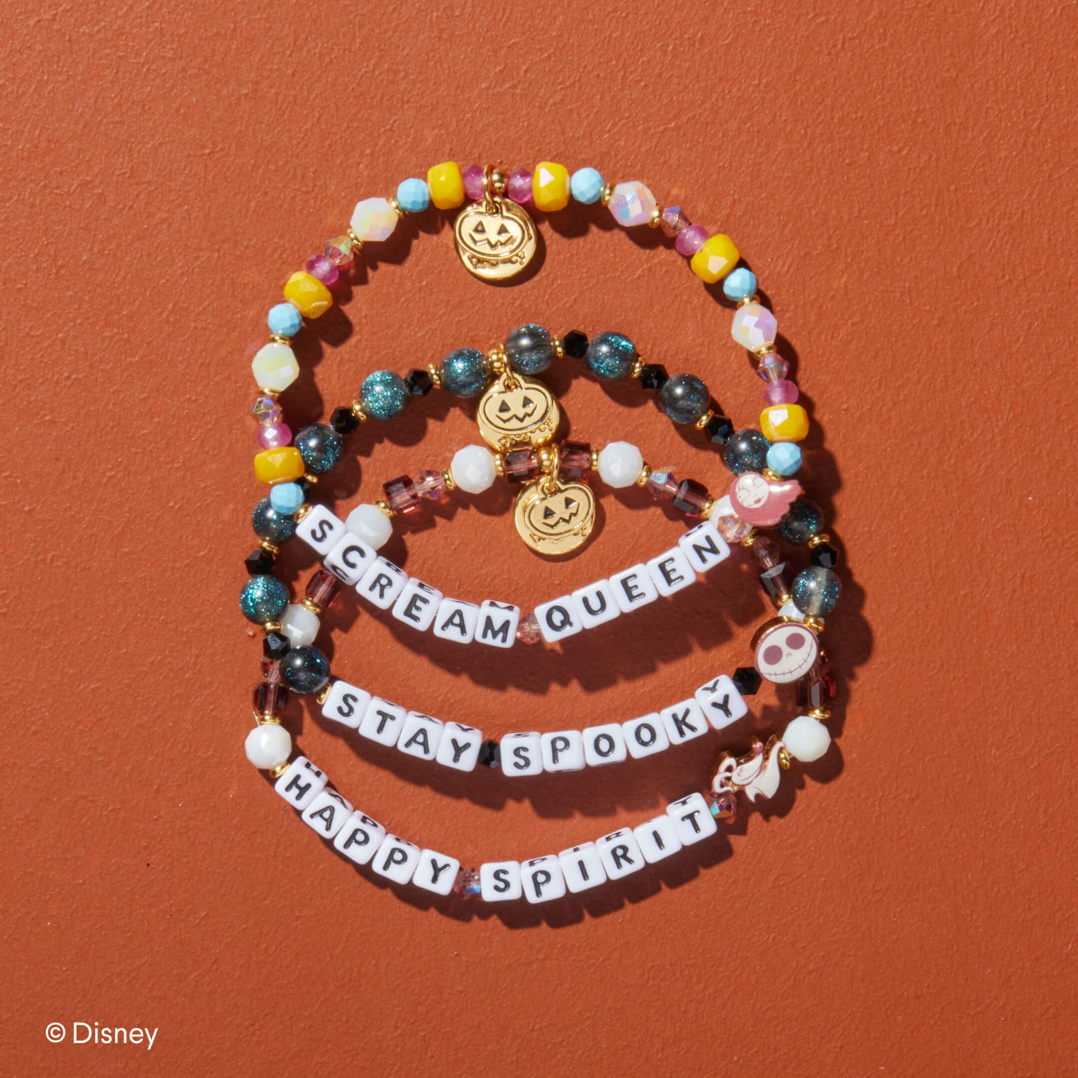 Colorful beaded bracelets with Halloween-themed charms on a brown background