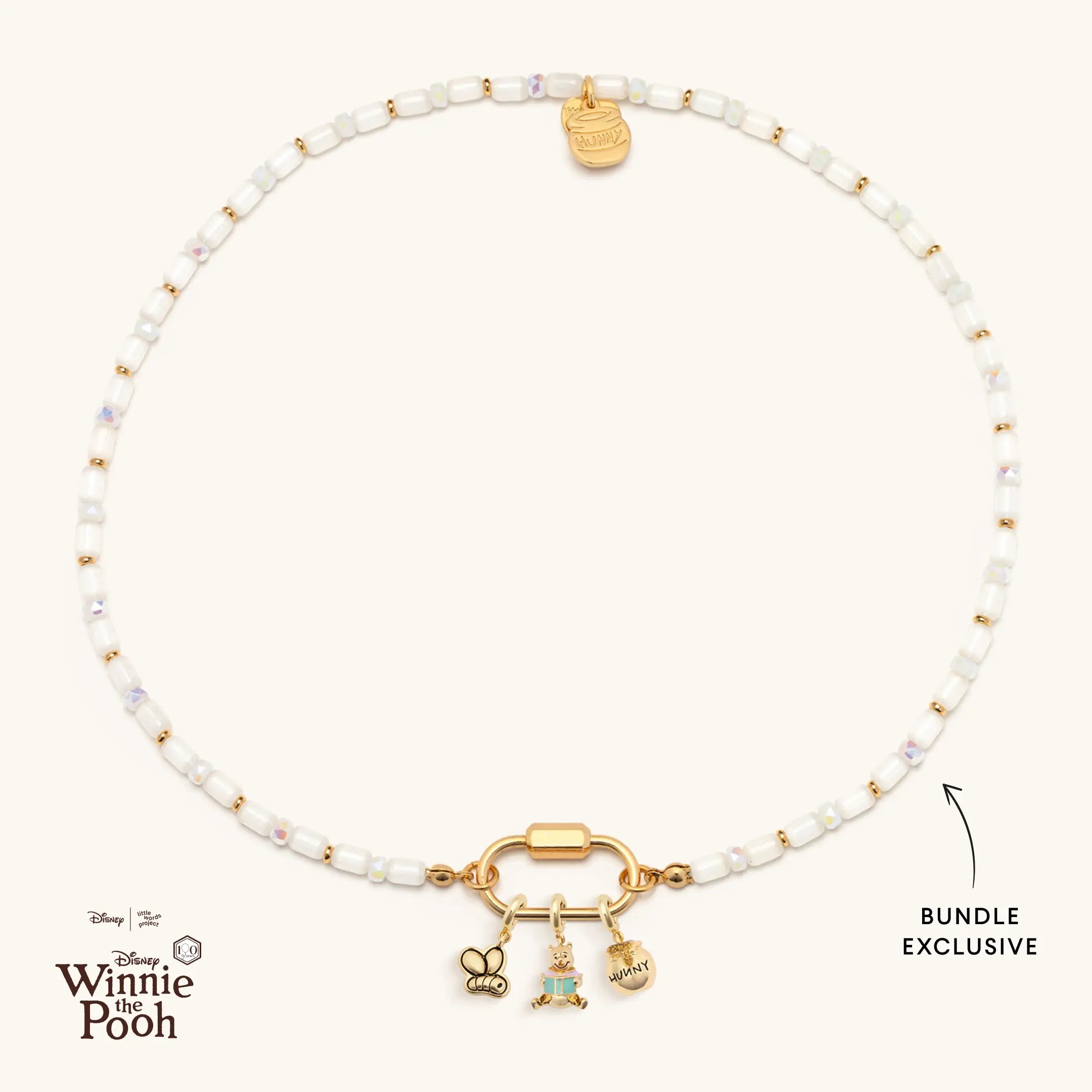 Necklace with gold charms and white beads on a white background, featuring Disney Winnie the Pooh logo.