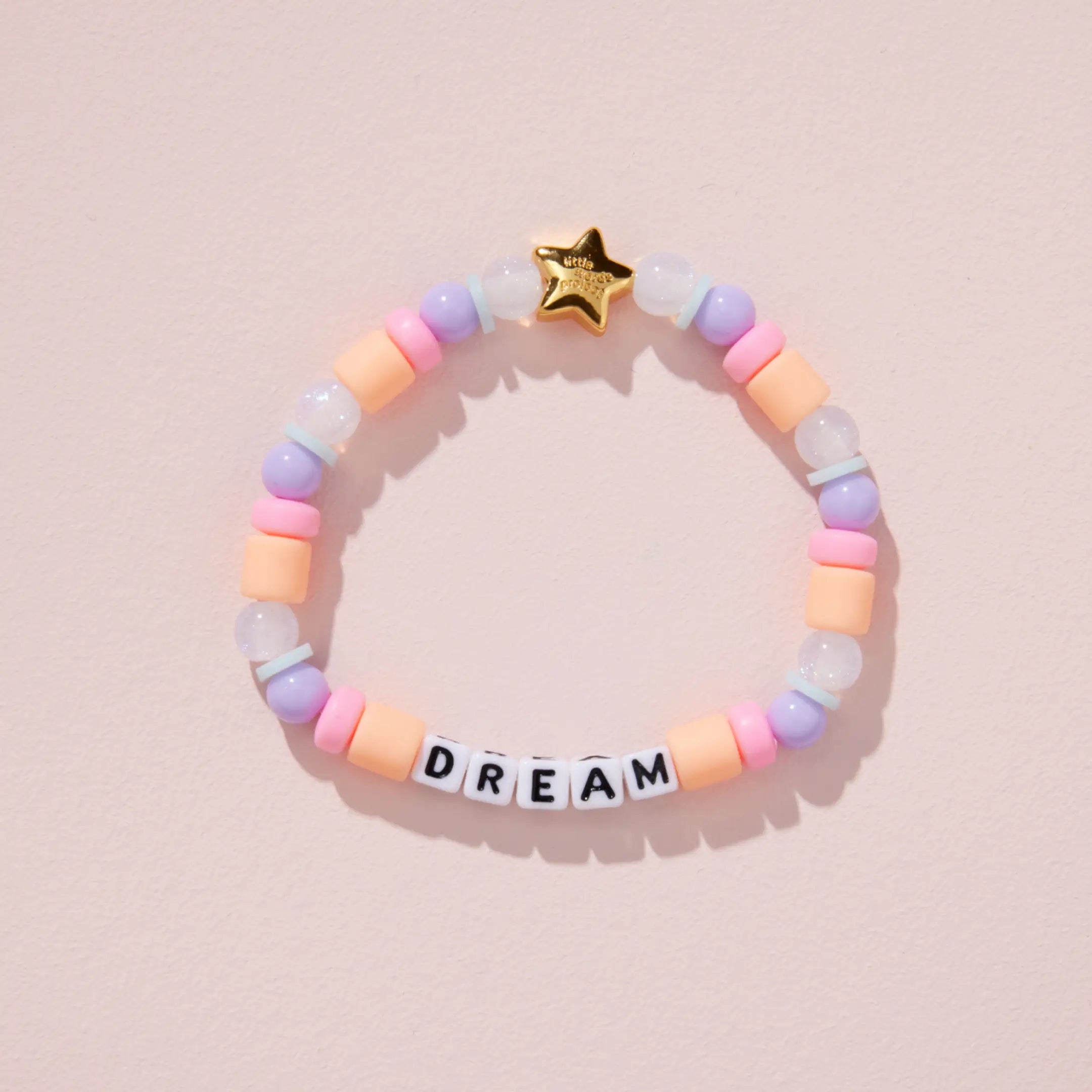 Colorful beaded bracelet with 'DREAM' on a pink background