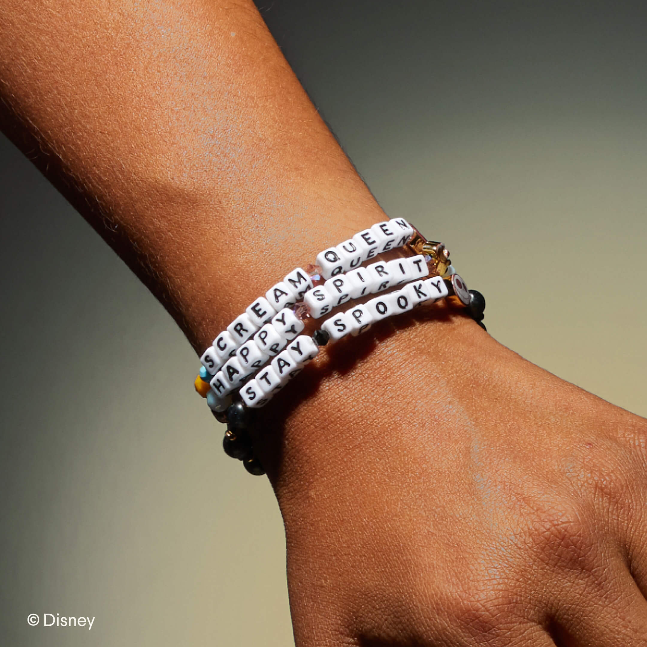 Bracelets with motivational phrases on a wrist against a neutral background