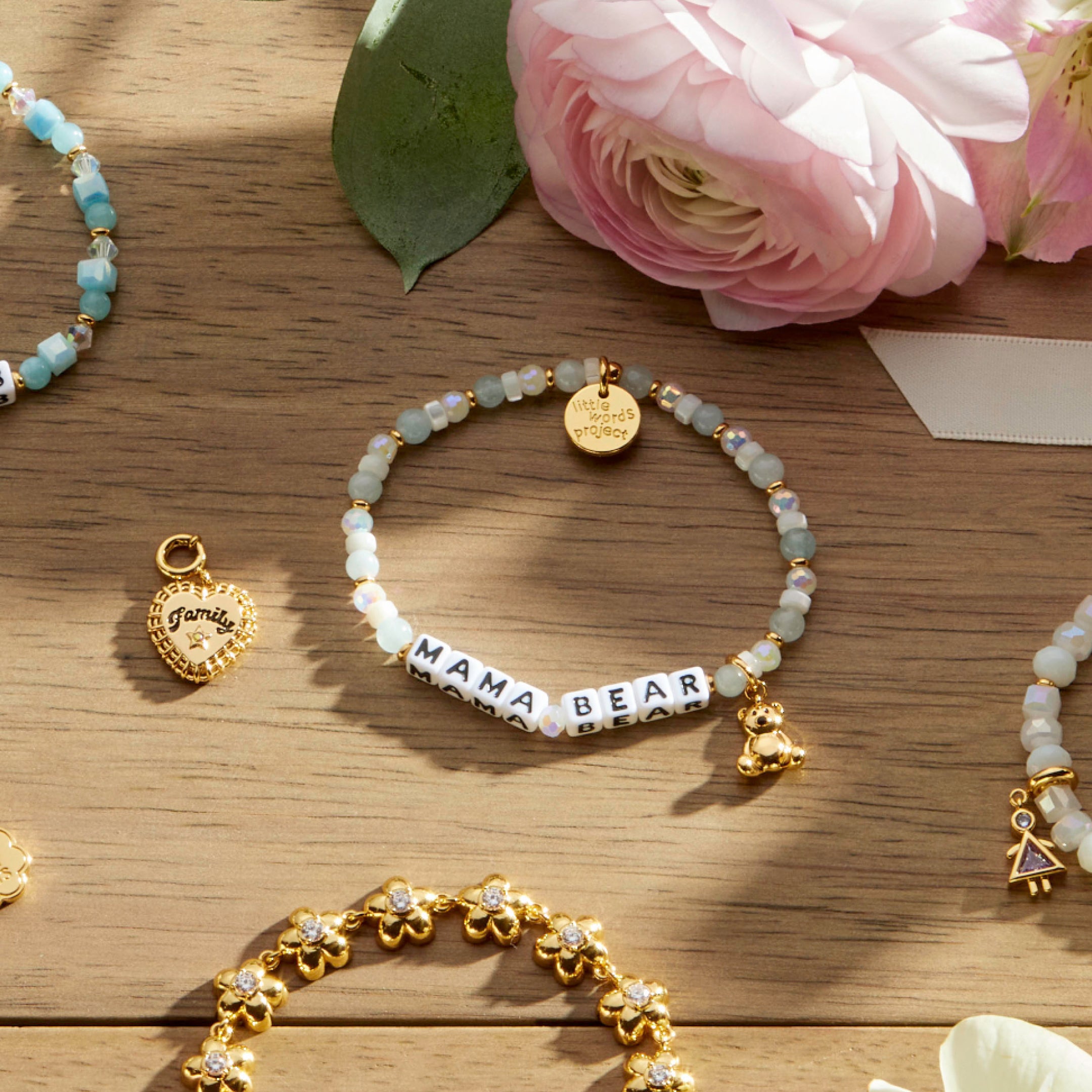 Bracelets with charms on a wooden surface with pink flowers