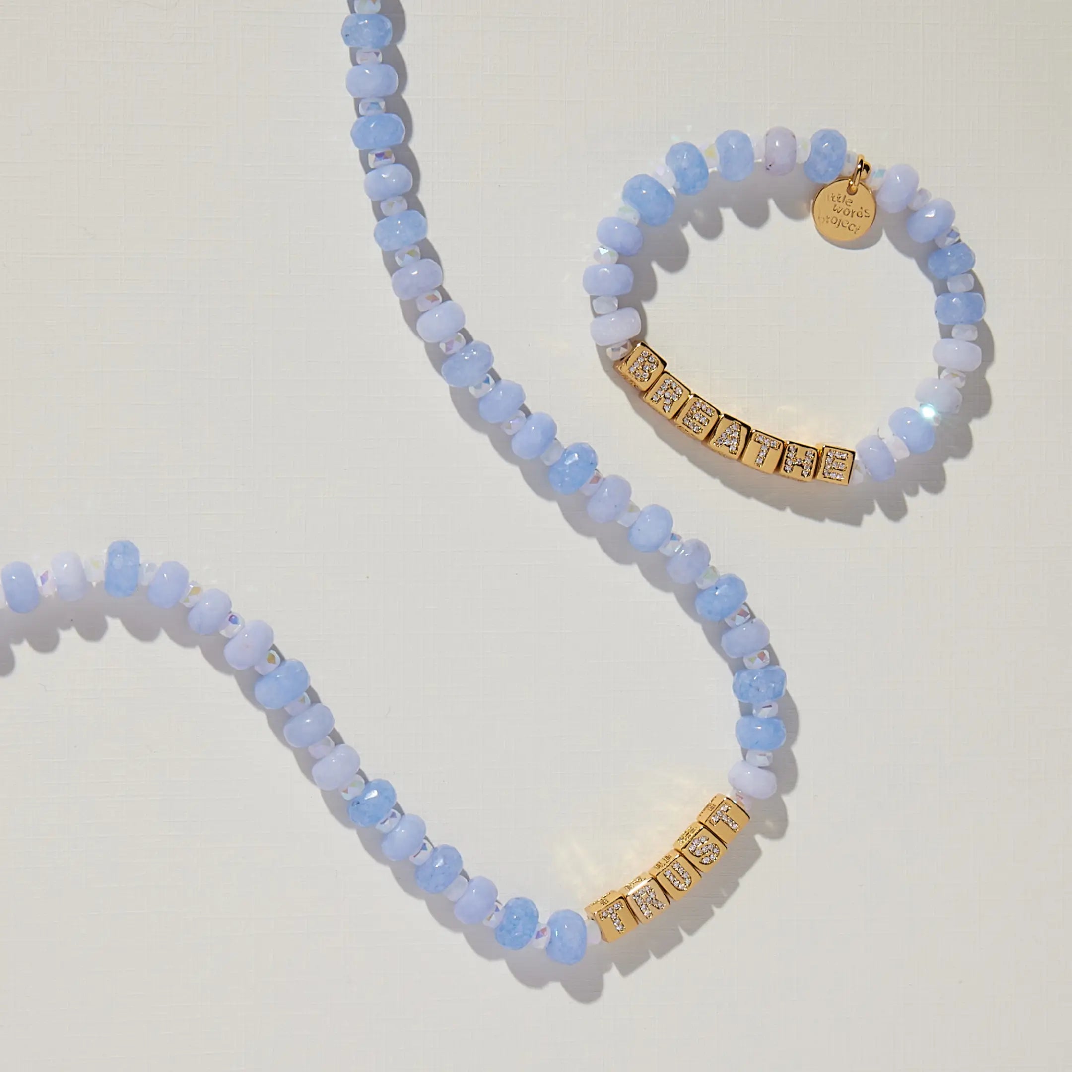 Blue beaded necklace and bracelet with gold accents on a light background