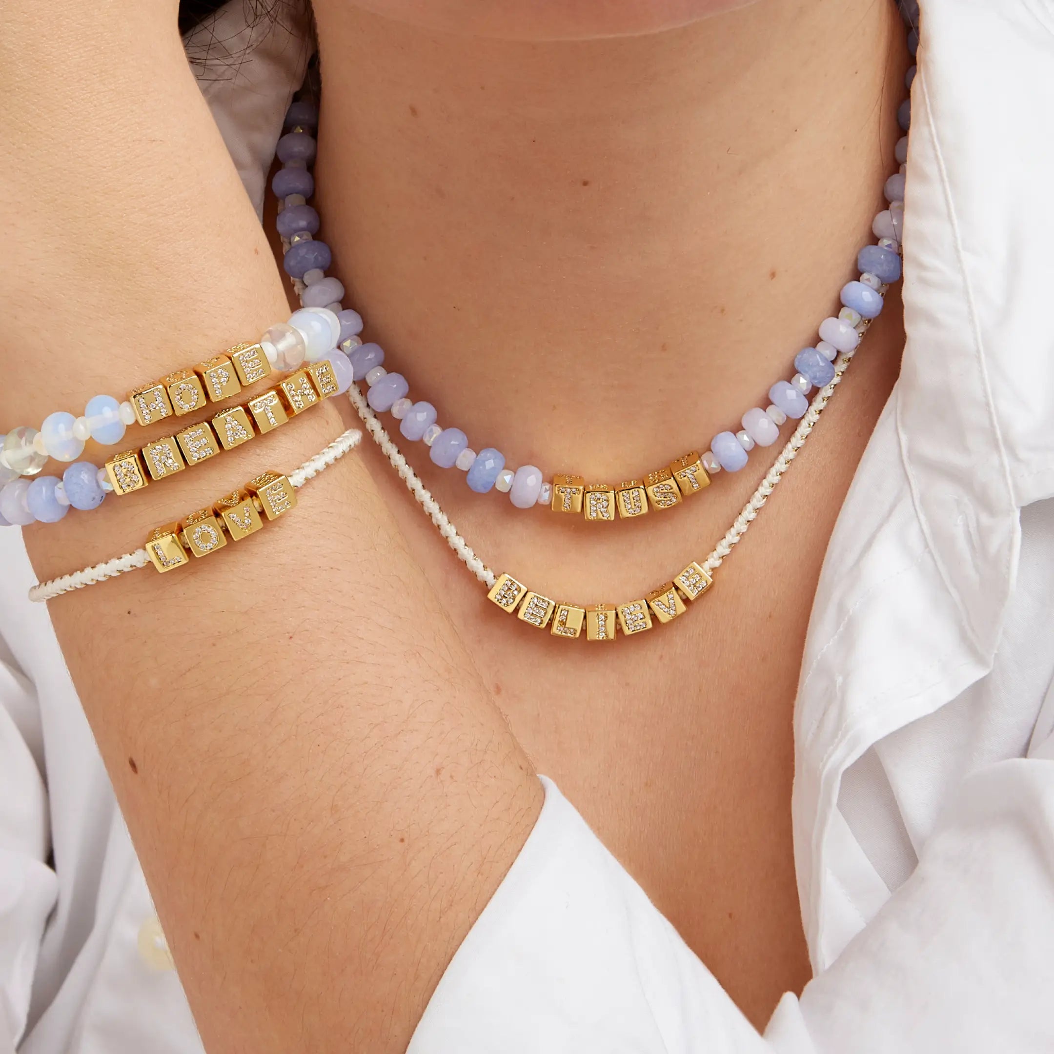 Necklaces and bracelets worn by a person against a white background