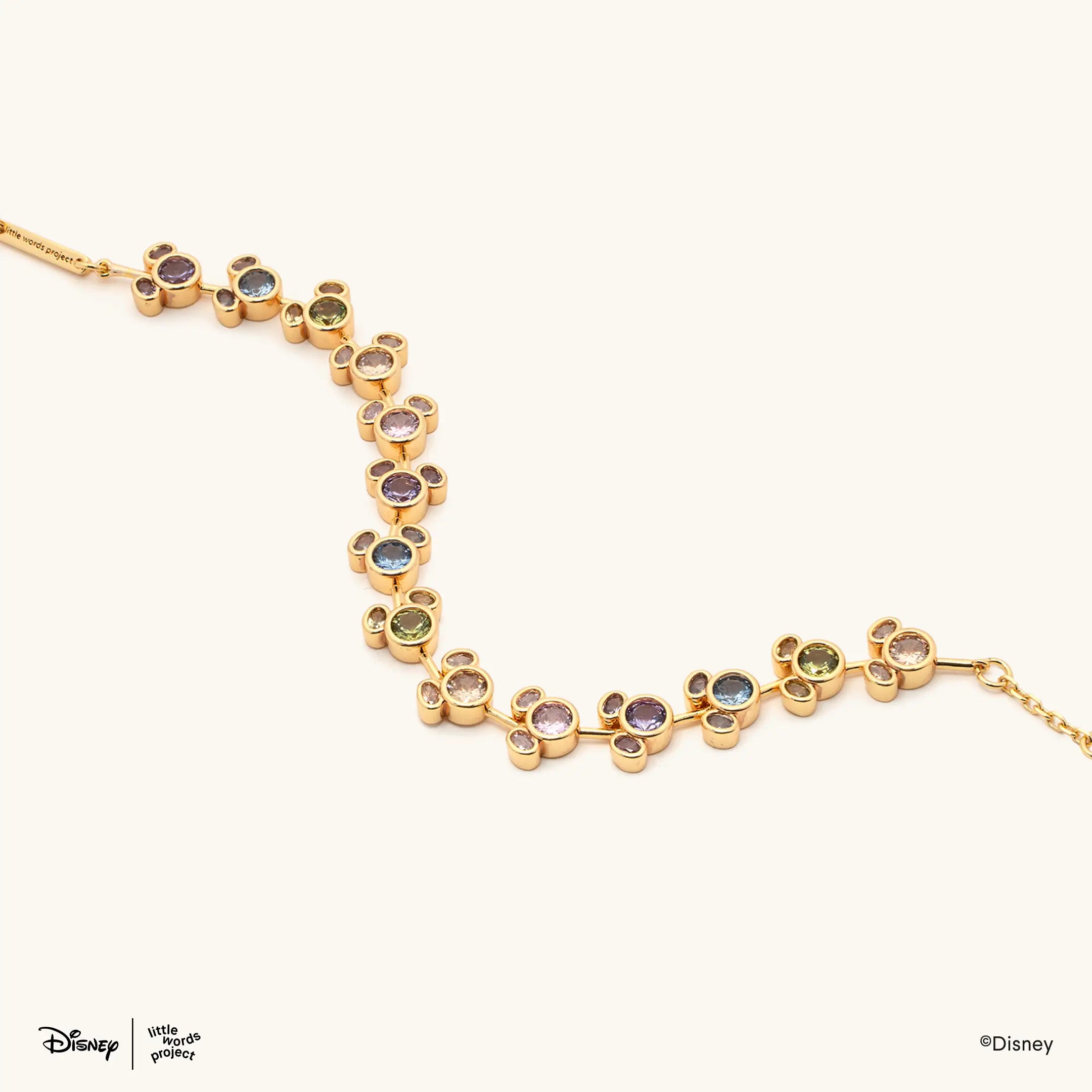 Mickey Mouse Rainbow Bracelet from Disney Mickey and Friends, flat lay on cream, gold plated chain of Mickey Mouse links set with multicolor crystals