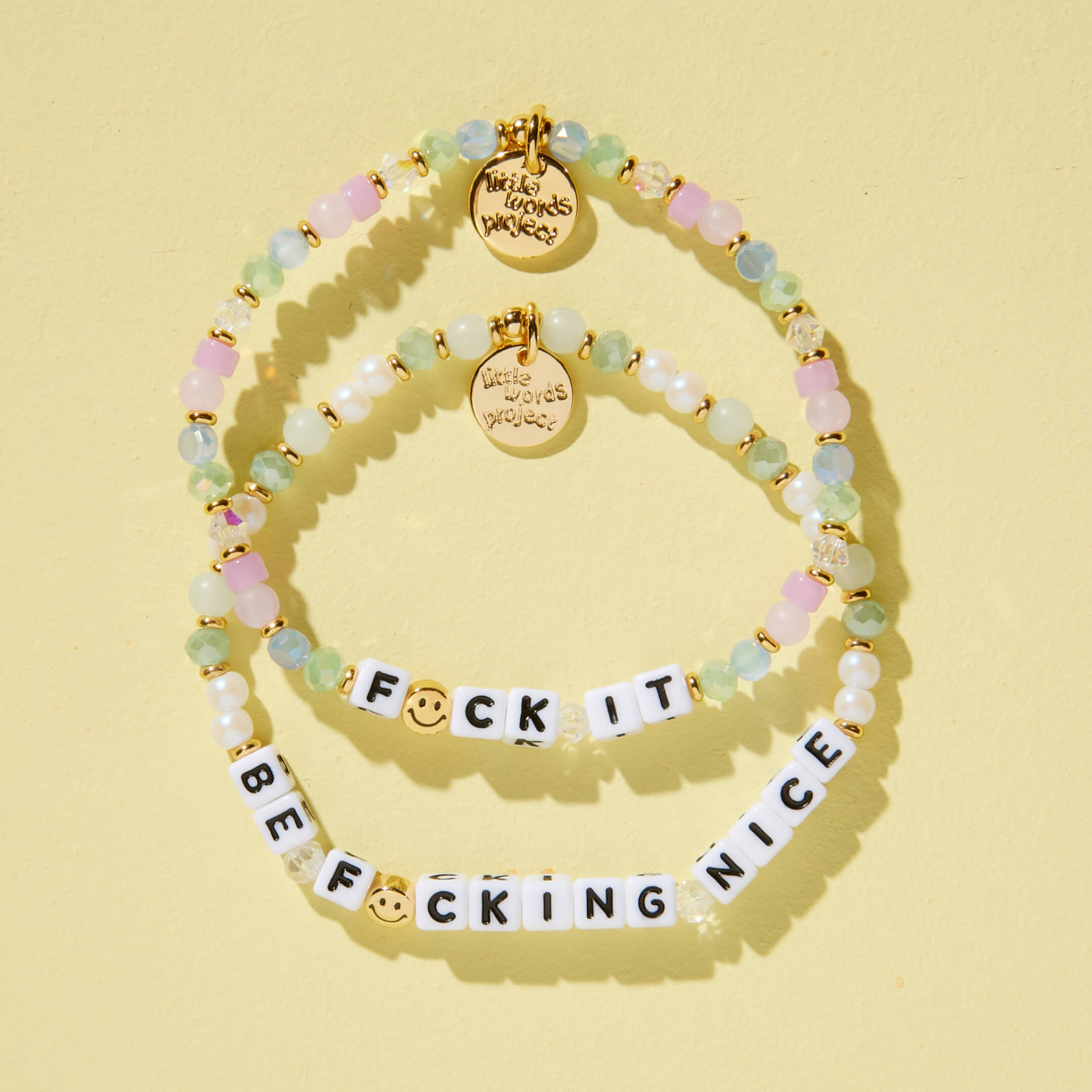 Two beaded bracelets with different messages on a yellow background