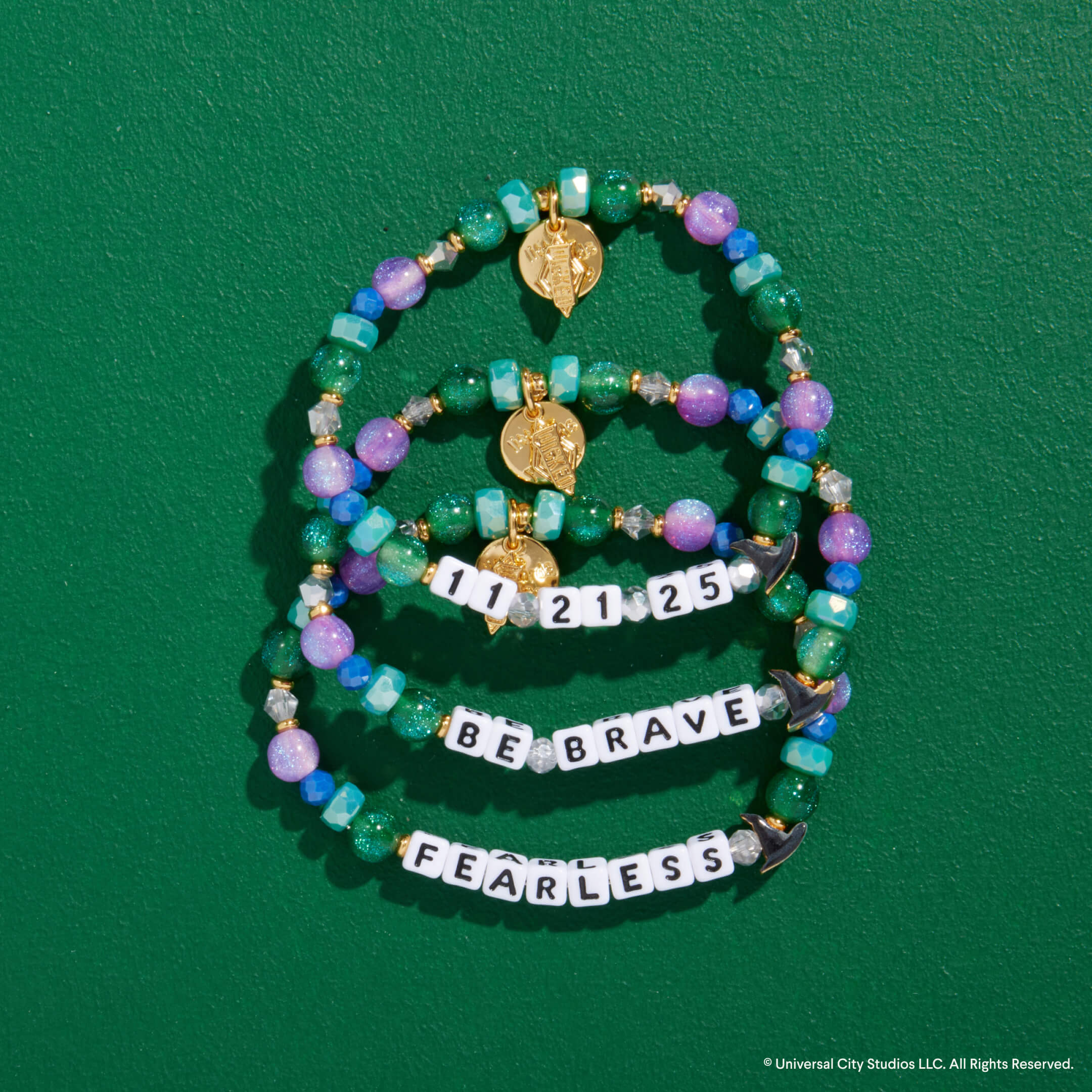 Stack of beaded bracelets with motivational text on a green background