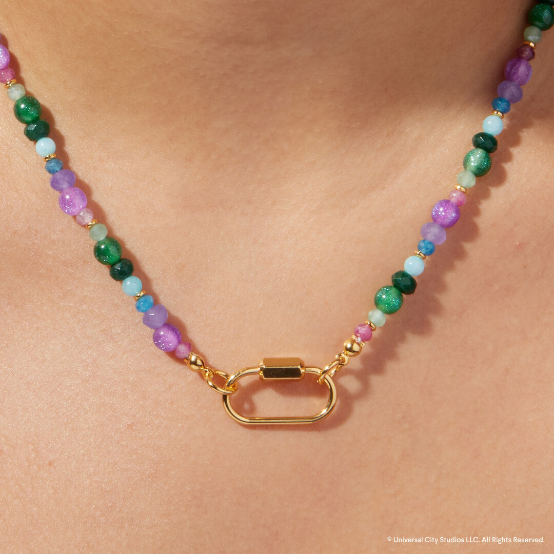 Multicolored beaded necklace with a gold clasp on a person's neck against a beige background