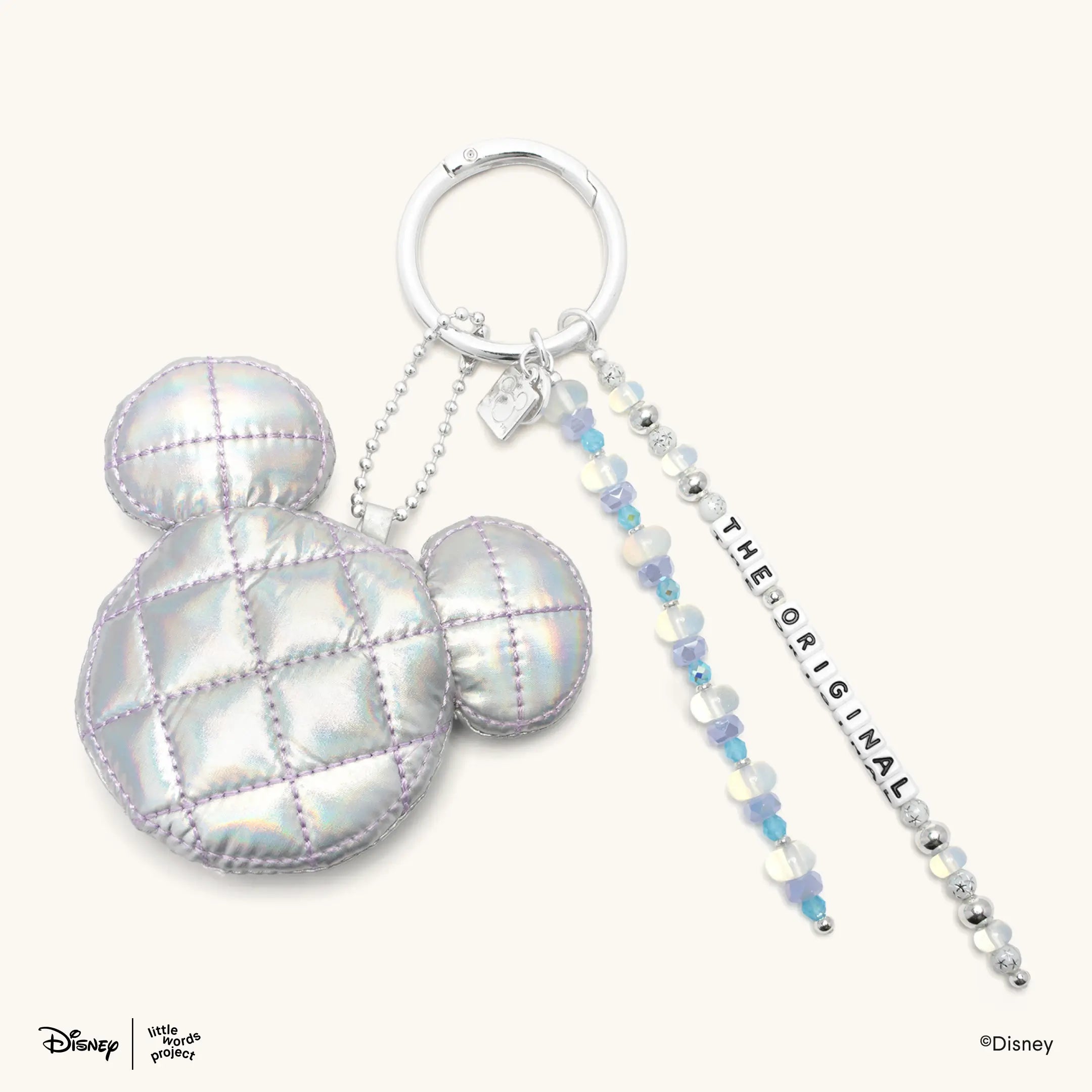 The OG Bag Charm from Disney Mickey and Friends on cream, iridescent quilted Mickey Mouse head on a silver ring with The Original letter bead strands