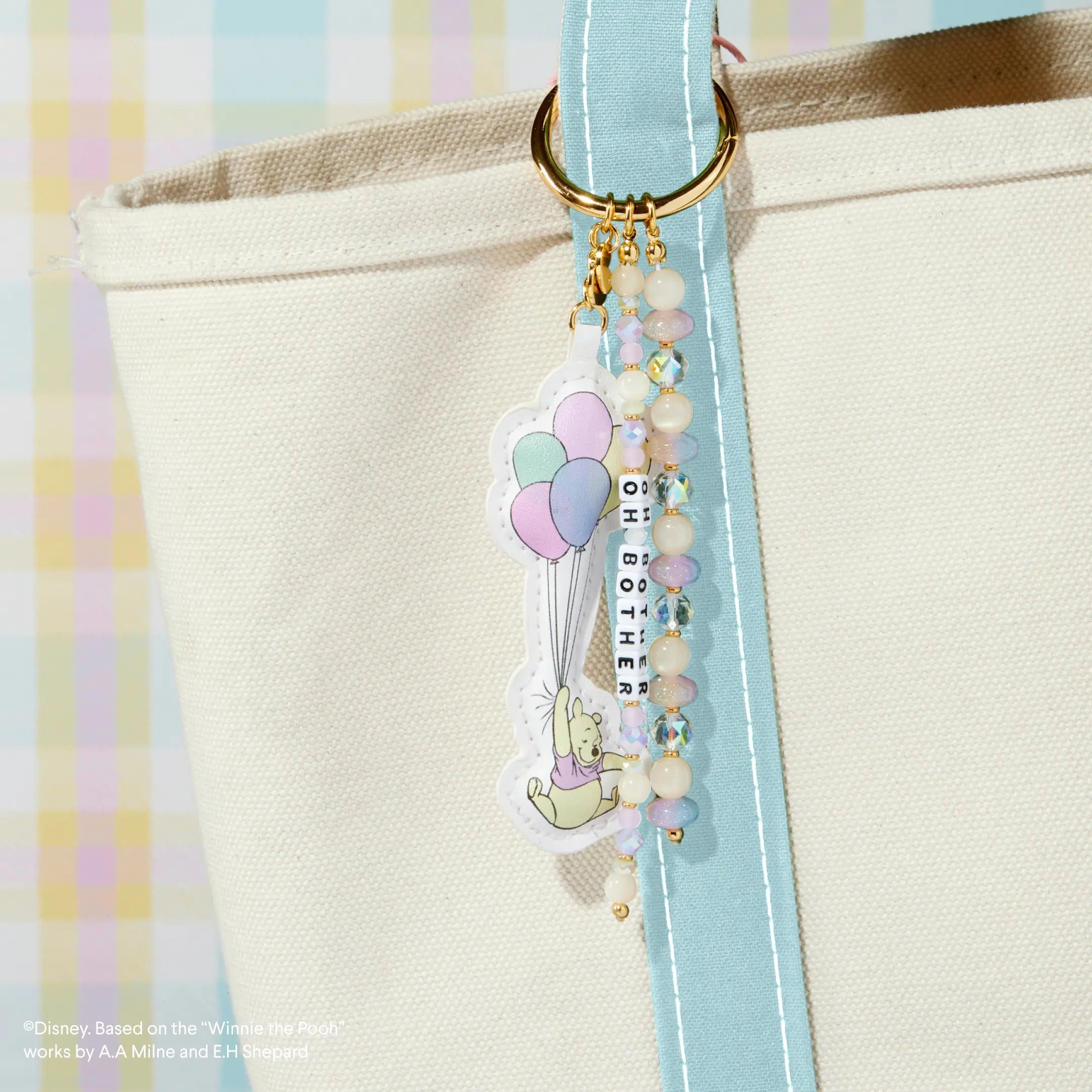 Decorative bag charm on a beige bag against a pastel plaid background
