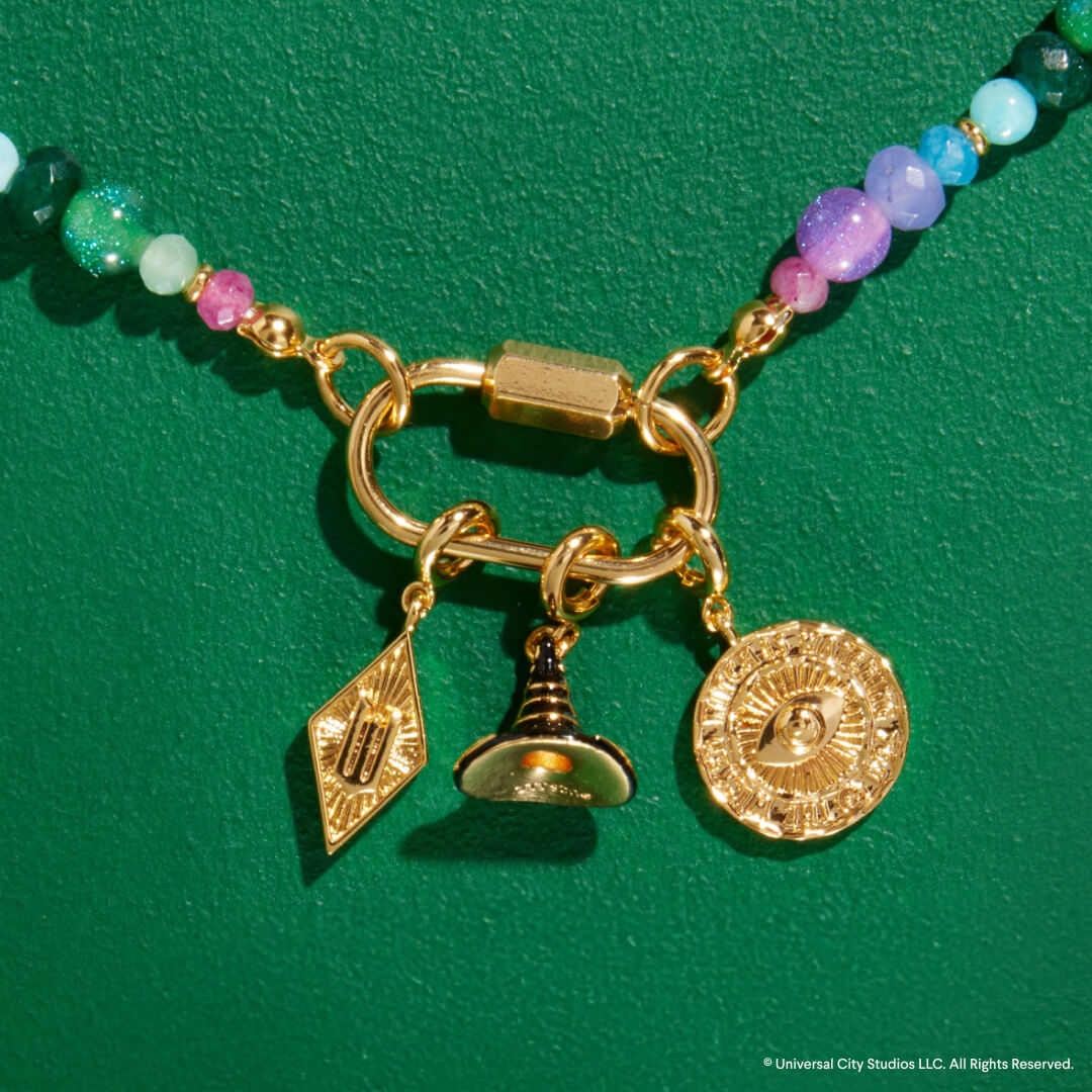 Necklace with gold charms and colorful beads on a green background