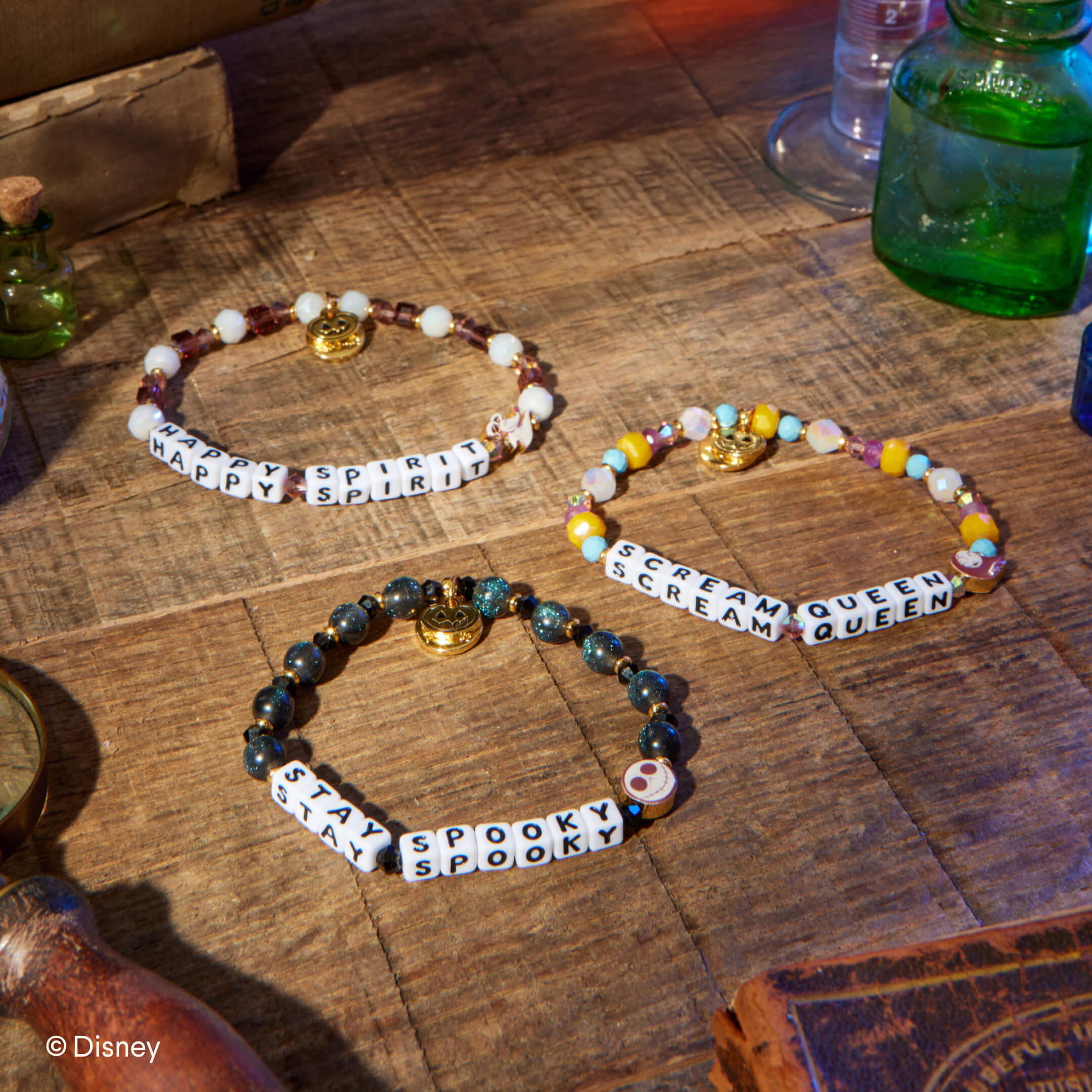 Three bracelets with Halloween-themed text on a wooden surface