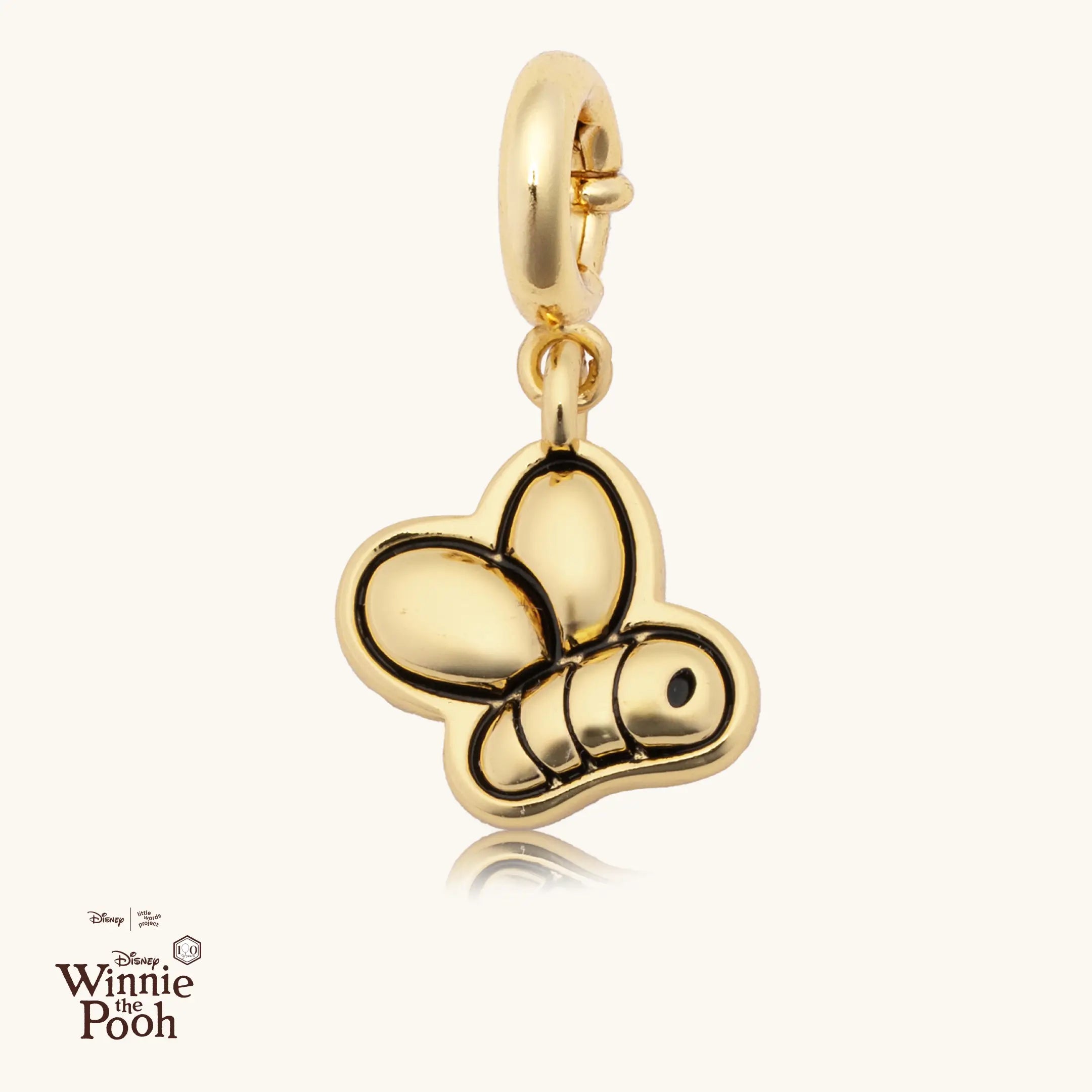 Gold bee-shaped charm on a white background with Disney Winnie the Pooh logo.