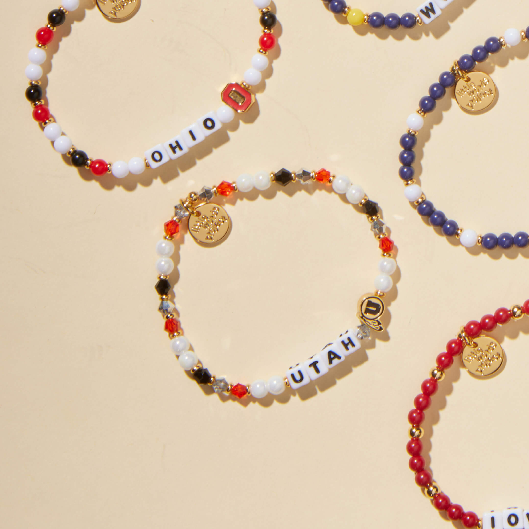 Colorful beaded bracelets with letter charms on a beige background