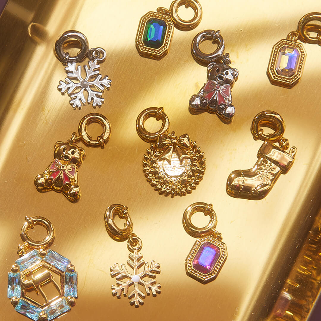 Collection of gold charms including snowflakes, bears, and stockings on a gold surface.