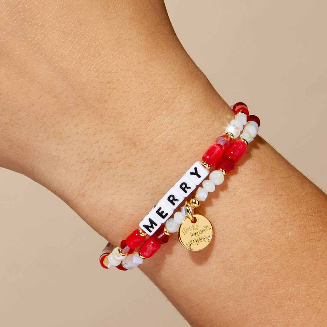 Bracelet with 'MERRY' word on a wrist against a beige background