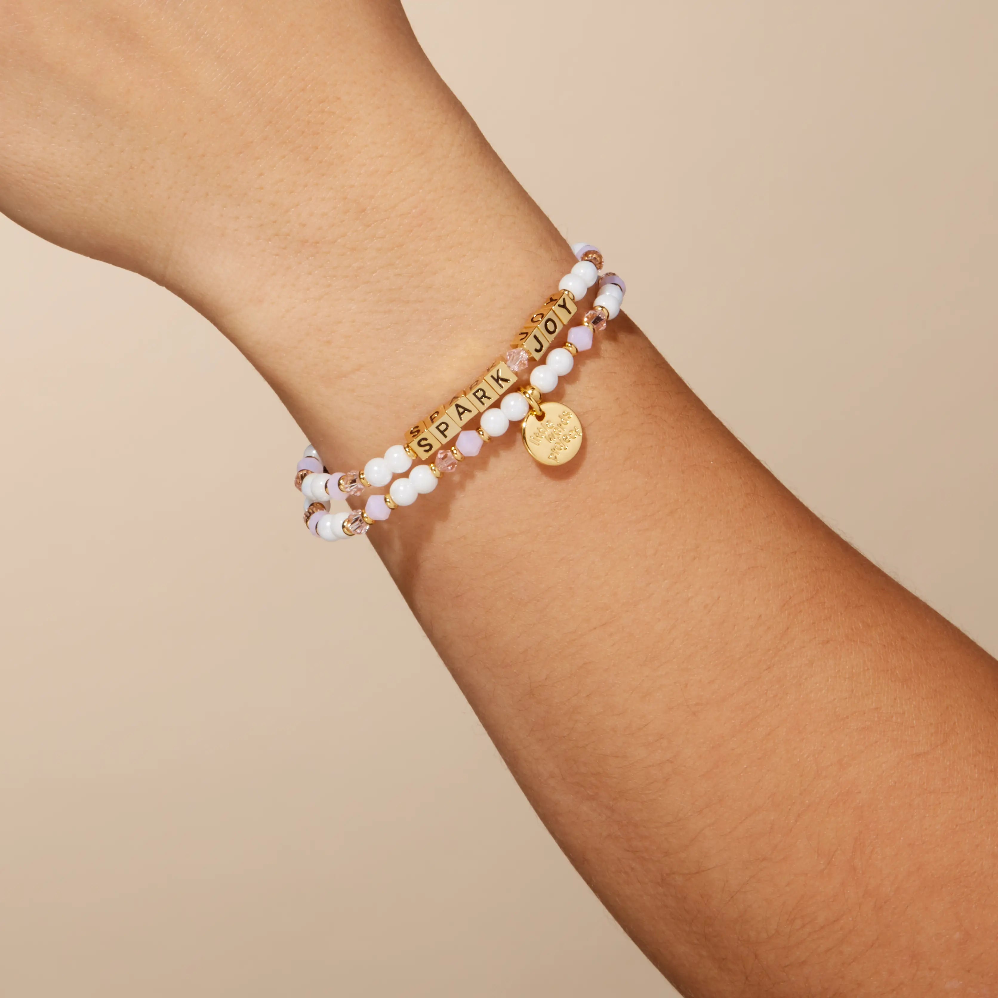 Stack of bracelets on a wrist with a neutral background