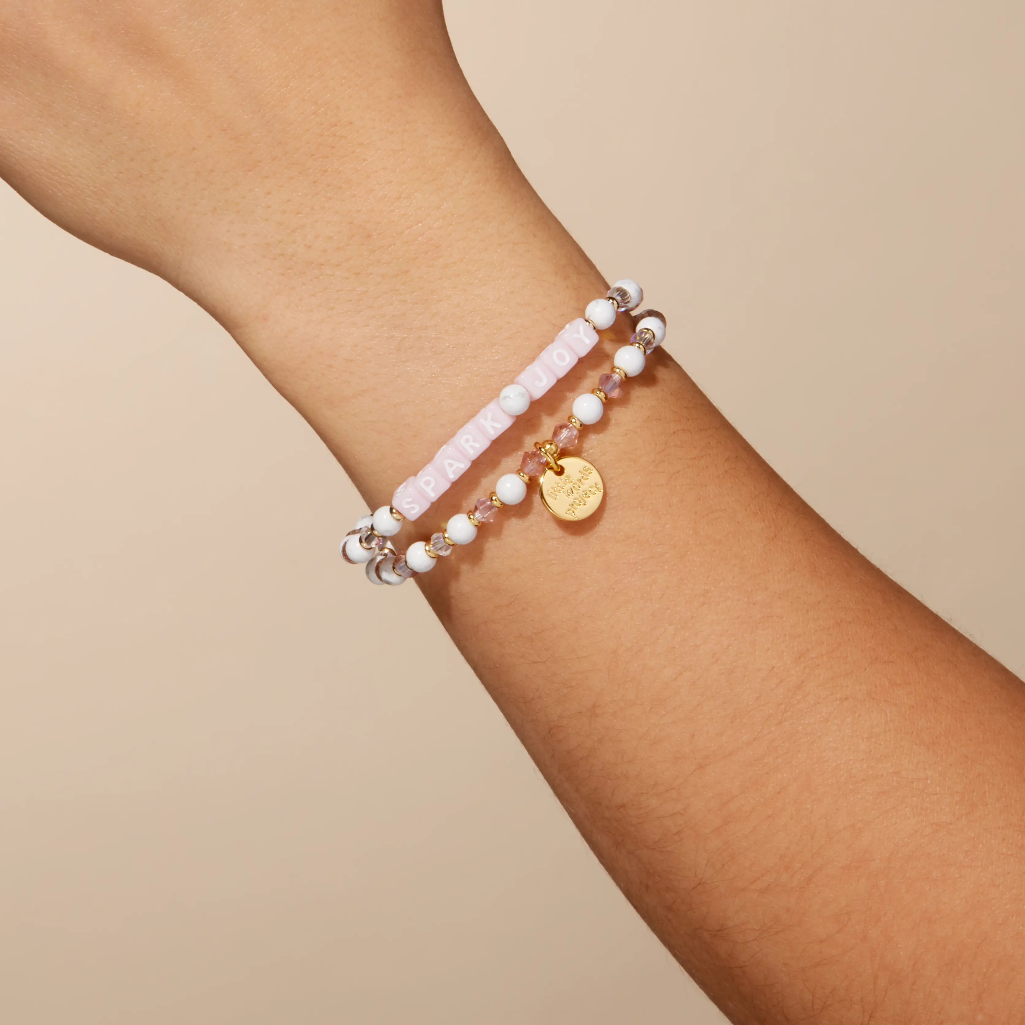 Stack of beaded bracelets on a wrist against a beige background