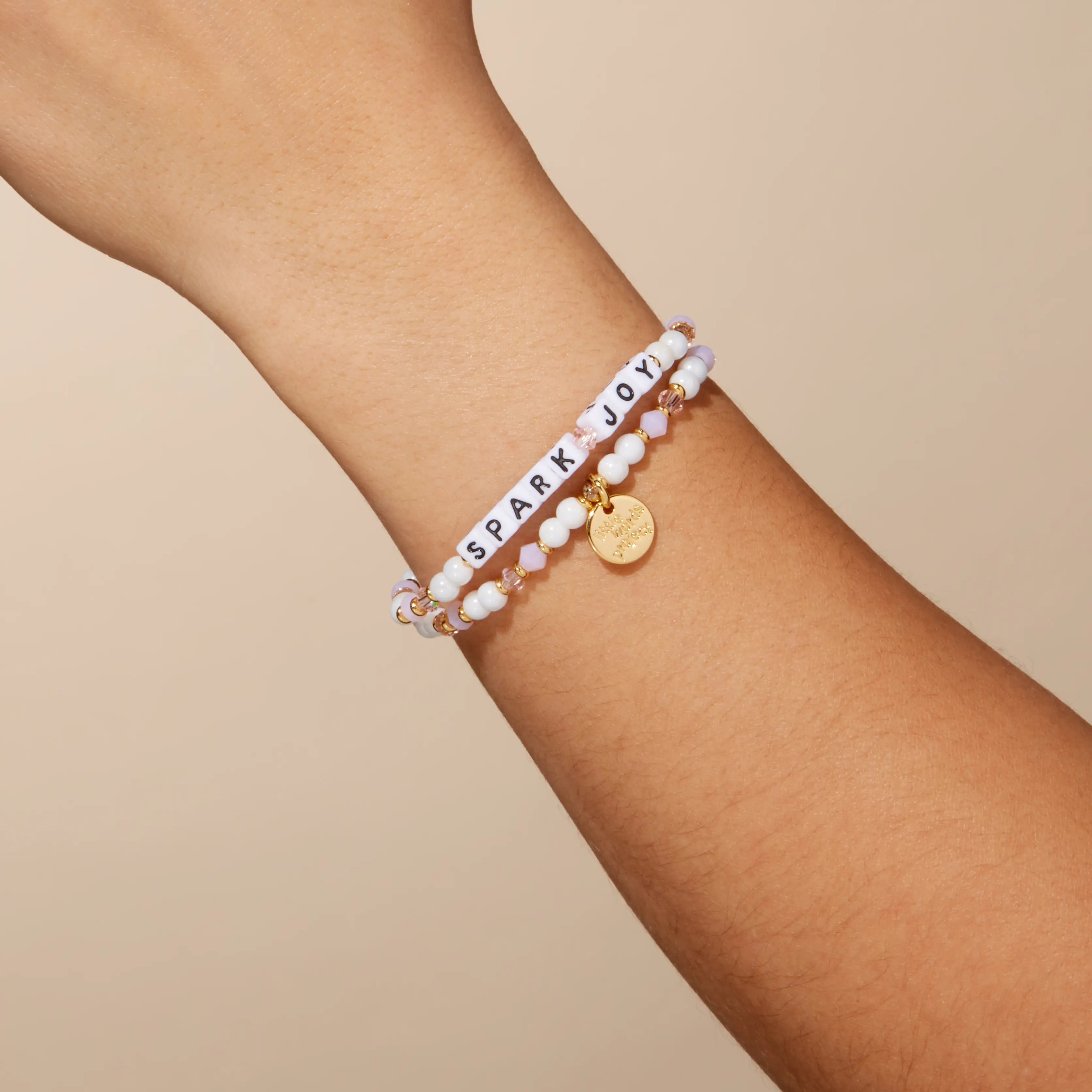 Bracelet with 'Spark Joy' on a wrist against a beige background