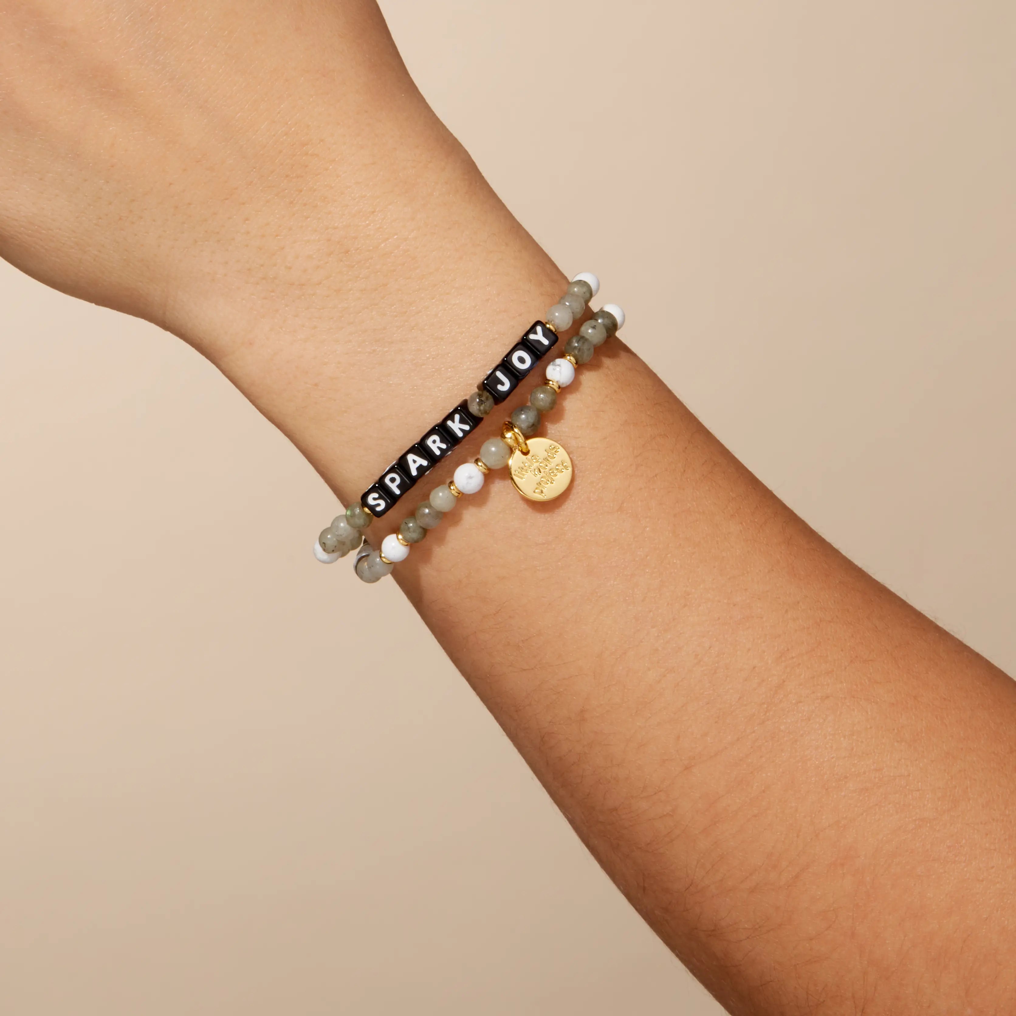 Bracelet with 'SPARK JOY' on a wrist against a beige background