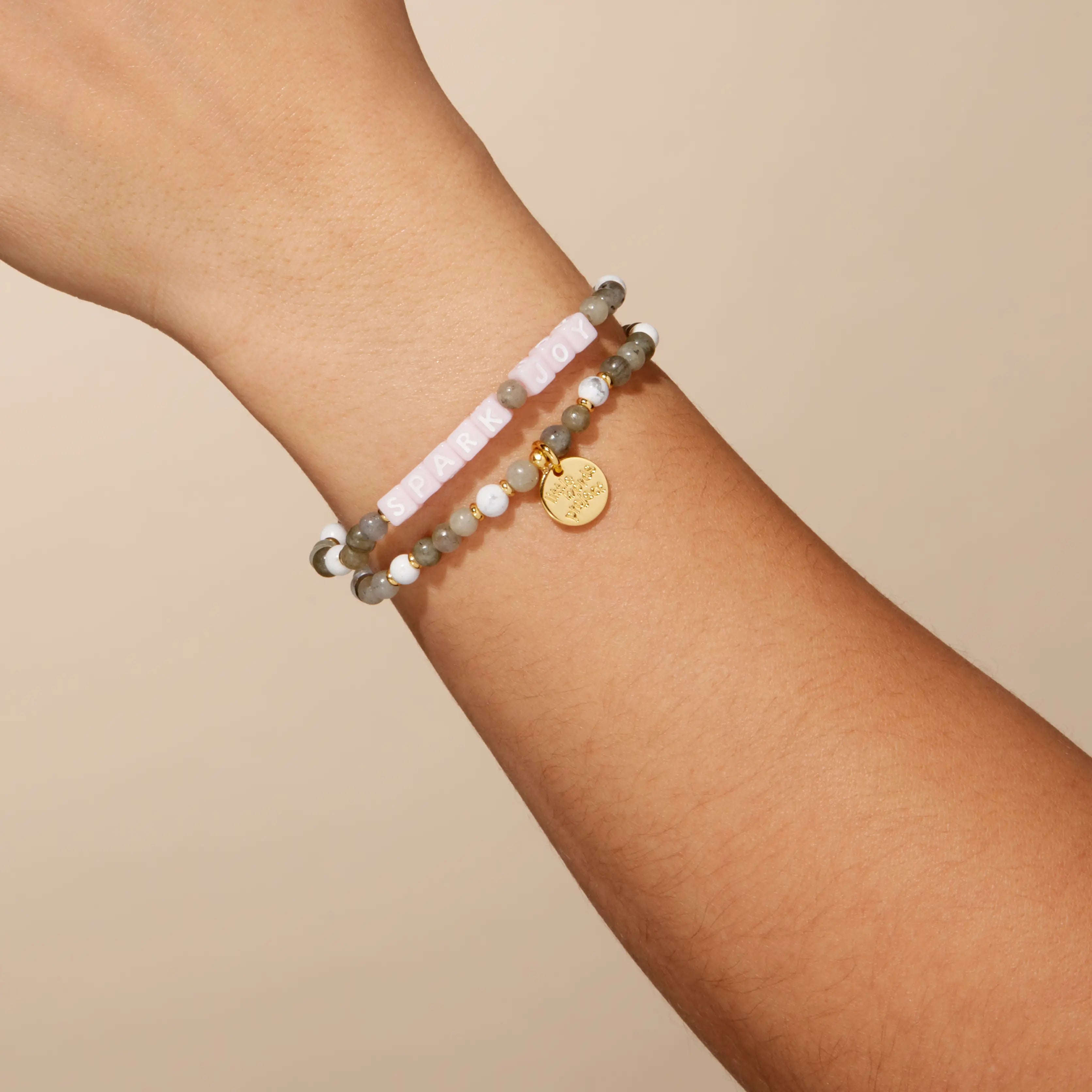 Stack of beaded bracelets on a wrist with a plain background
