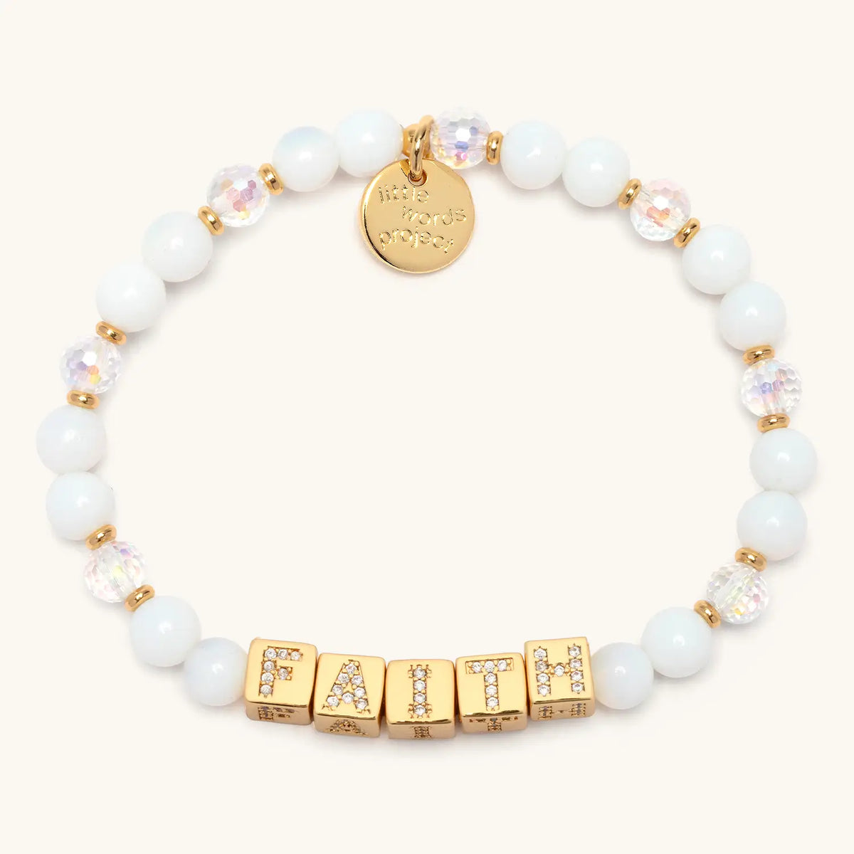 BOLDER Faith Bracelet in the Icicle Energy bead pattern, gold CZ letter blocks with white glass beads and clear iridescent faceted crystals with gold accents, flat-lay on cream background