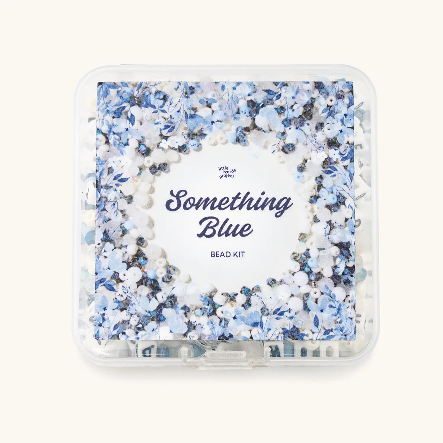 Front view of the clear Something Blue bead kit box with Little Words Project label, packed with blue, white, and navy beads