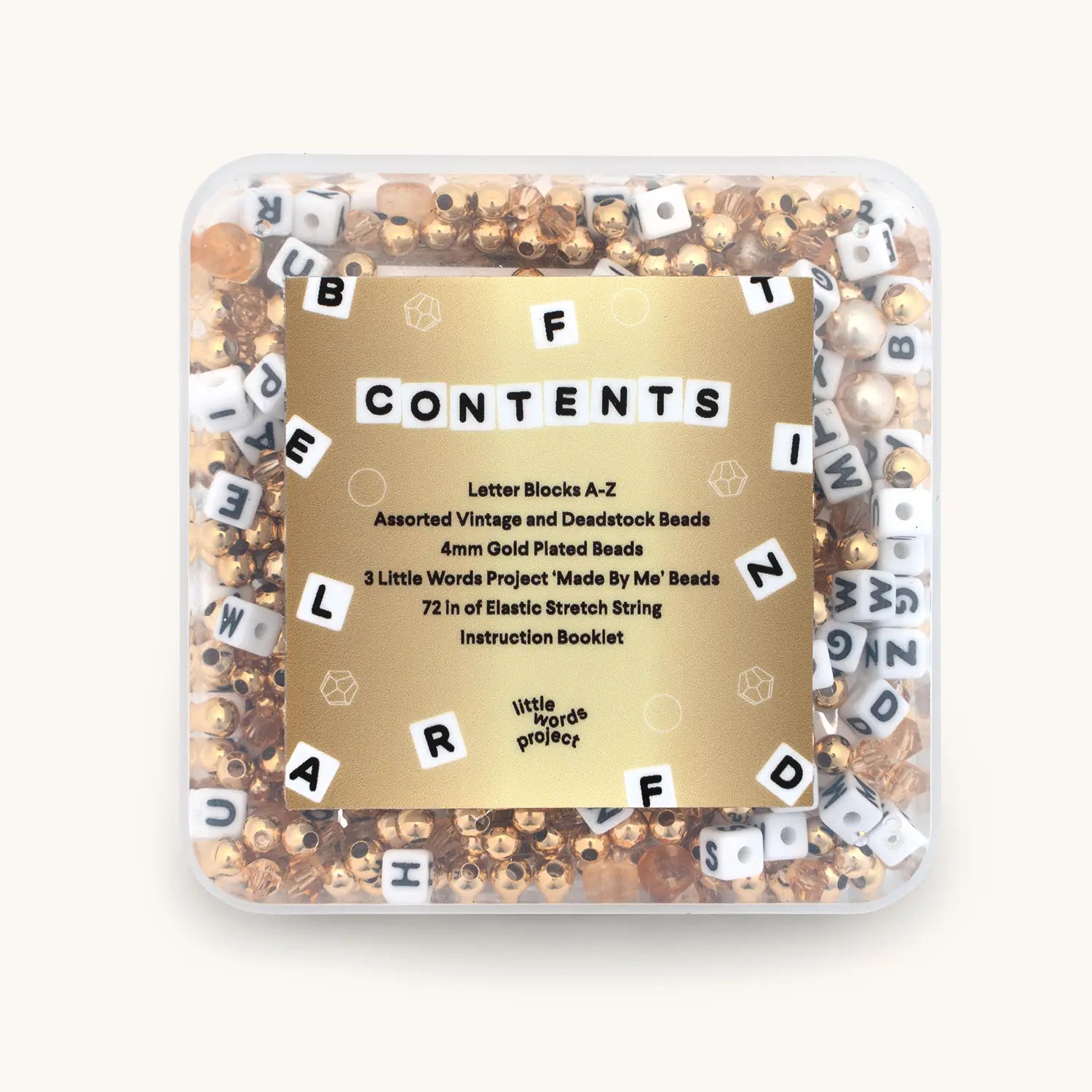 Container of letter blocks and beads with a gold label on a white background