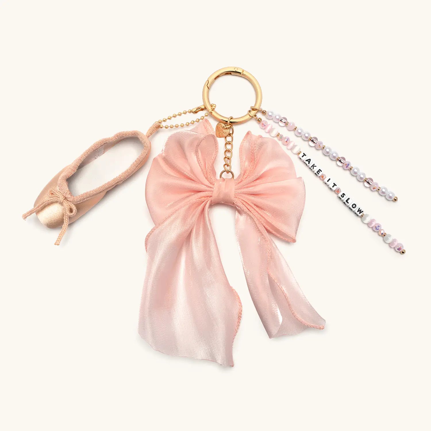 Take It Slow bag charm with pink satin bow and beaded tassel, flat lay