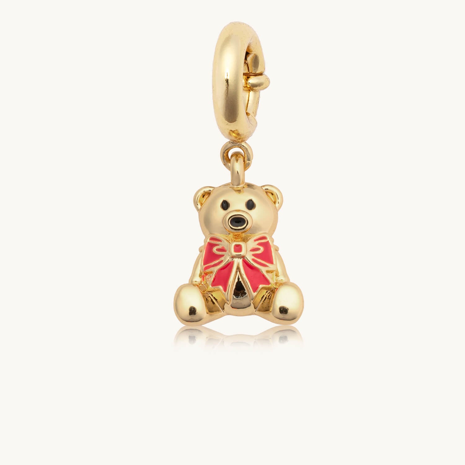 Gold teddy bear charm with a red bow on a white background