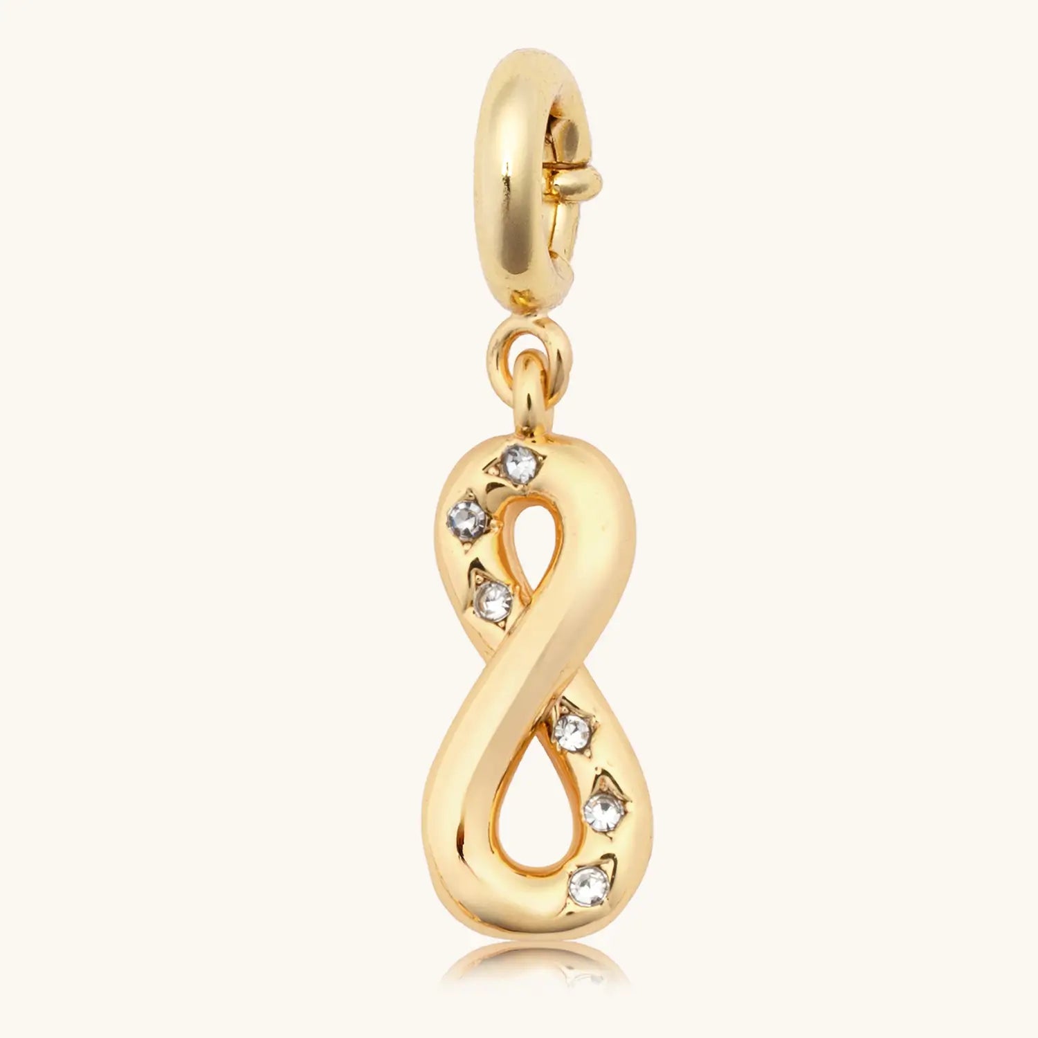 Gold infinity charm with embedded stones on a white background