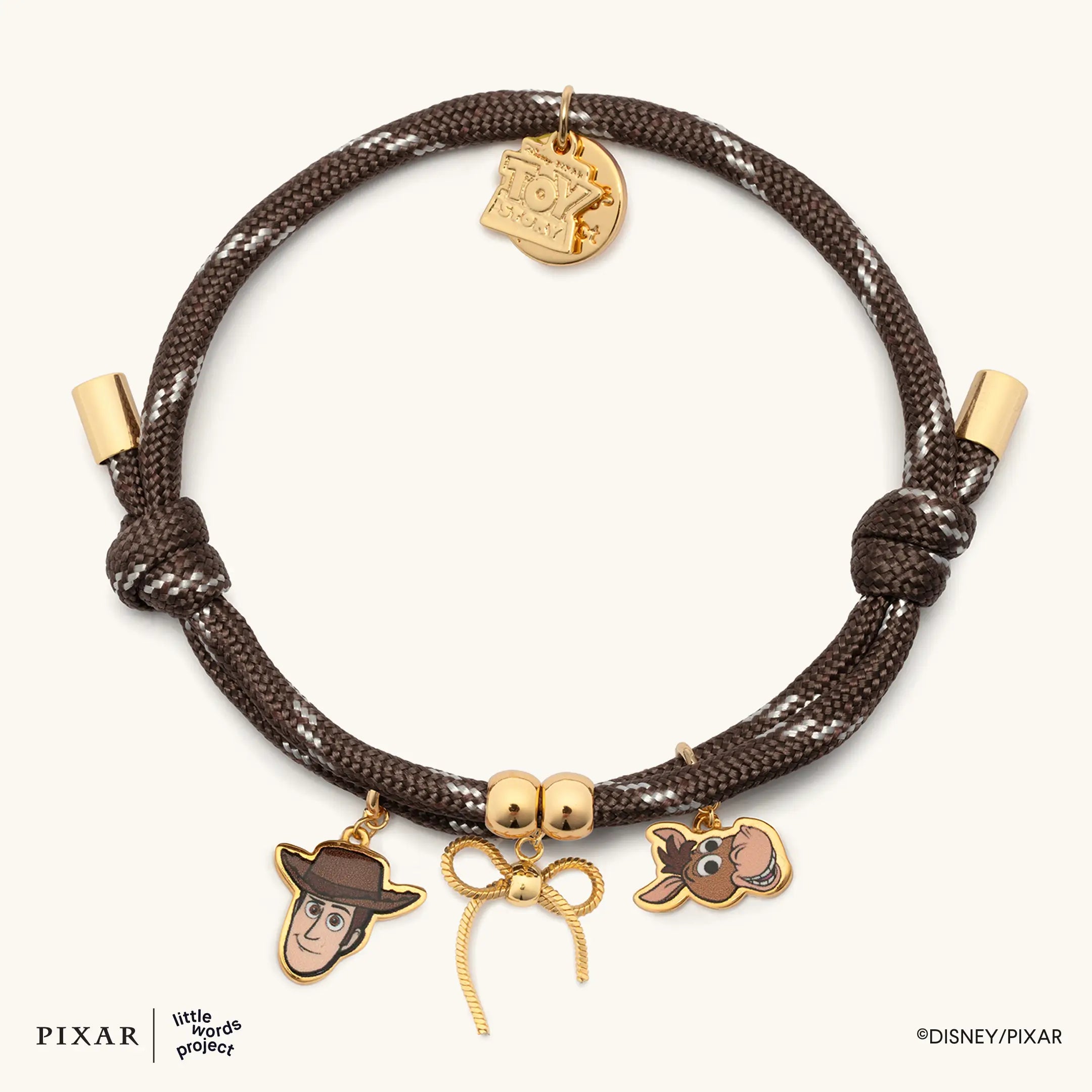 Woody's Round-Up brown corded Toy Story bracelet with gold Woody, bow and Bullseye charms, flat lay