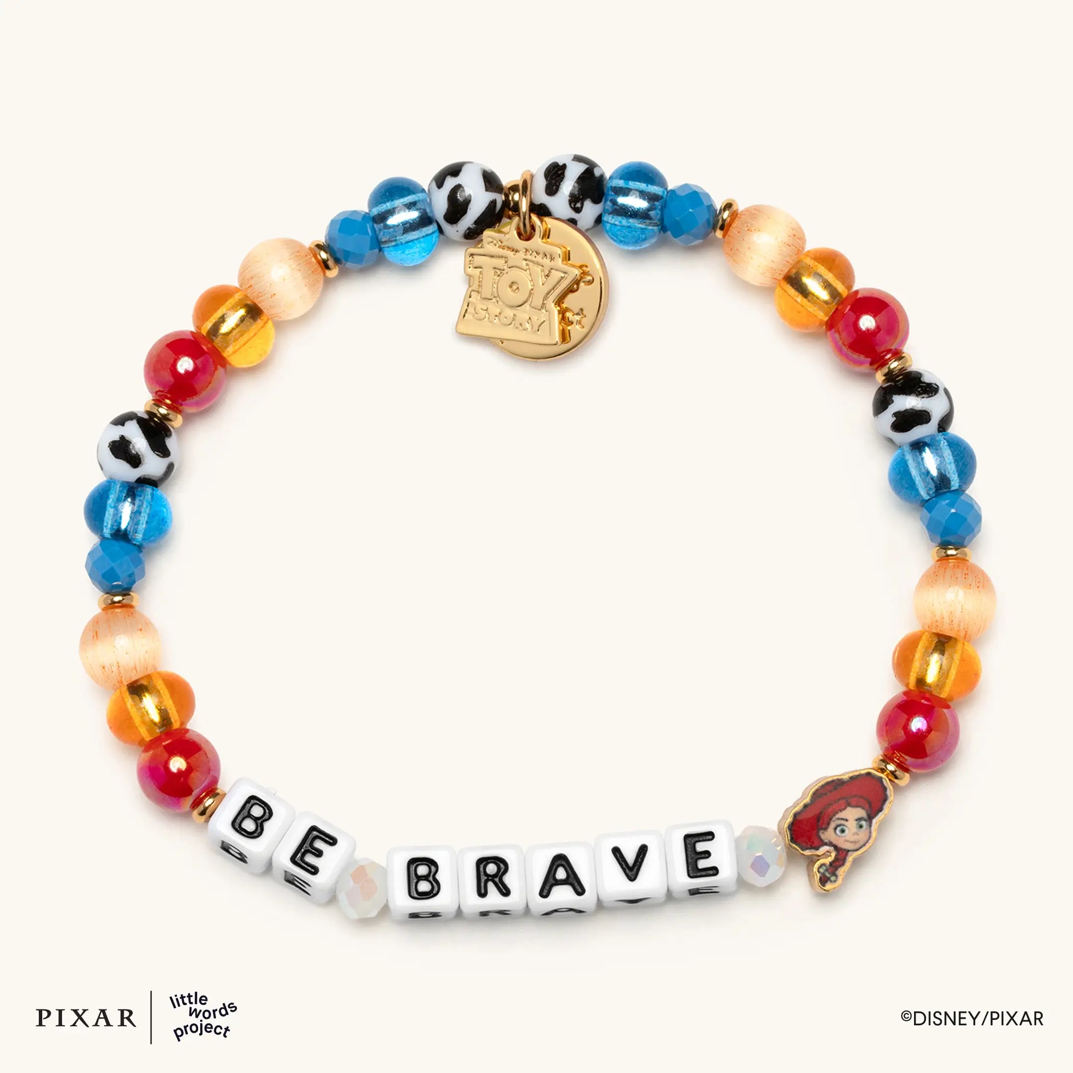 Be Brave Toy Story bracelet, blue, red and cow-print beads spelling BE BRAVE with a gold Jessie charm, flat lay