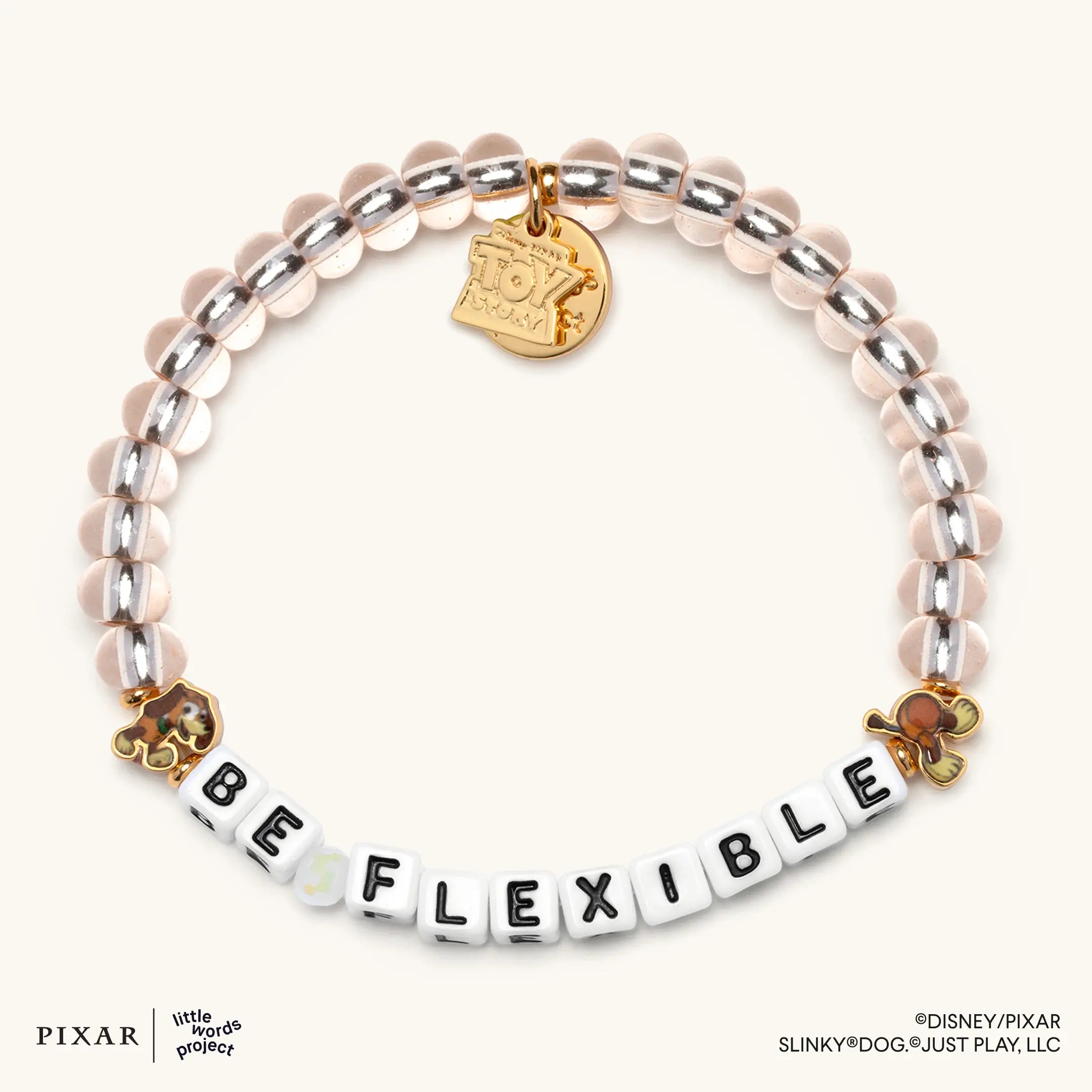 Be Flexible Toy Story bracelet, silver and clear beads spelling BE FLEXIBLE with gold Slinky Dog charms, flat lay