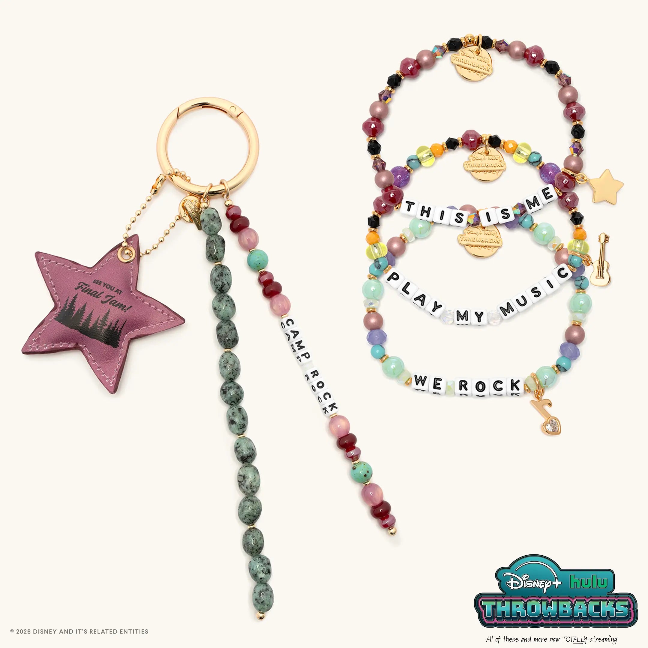 Camp Rock Set from Disney+ Hulu Throwbacks with the Camp Rock bag charm and the This Is Me, Play My Music, and We Rock bracelets, flat lay on cream