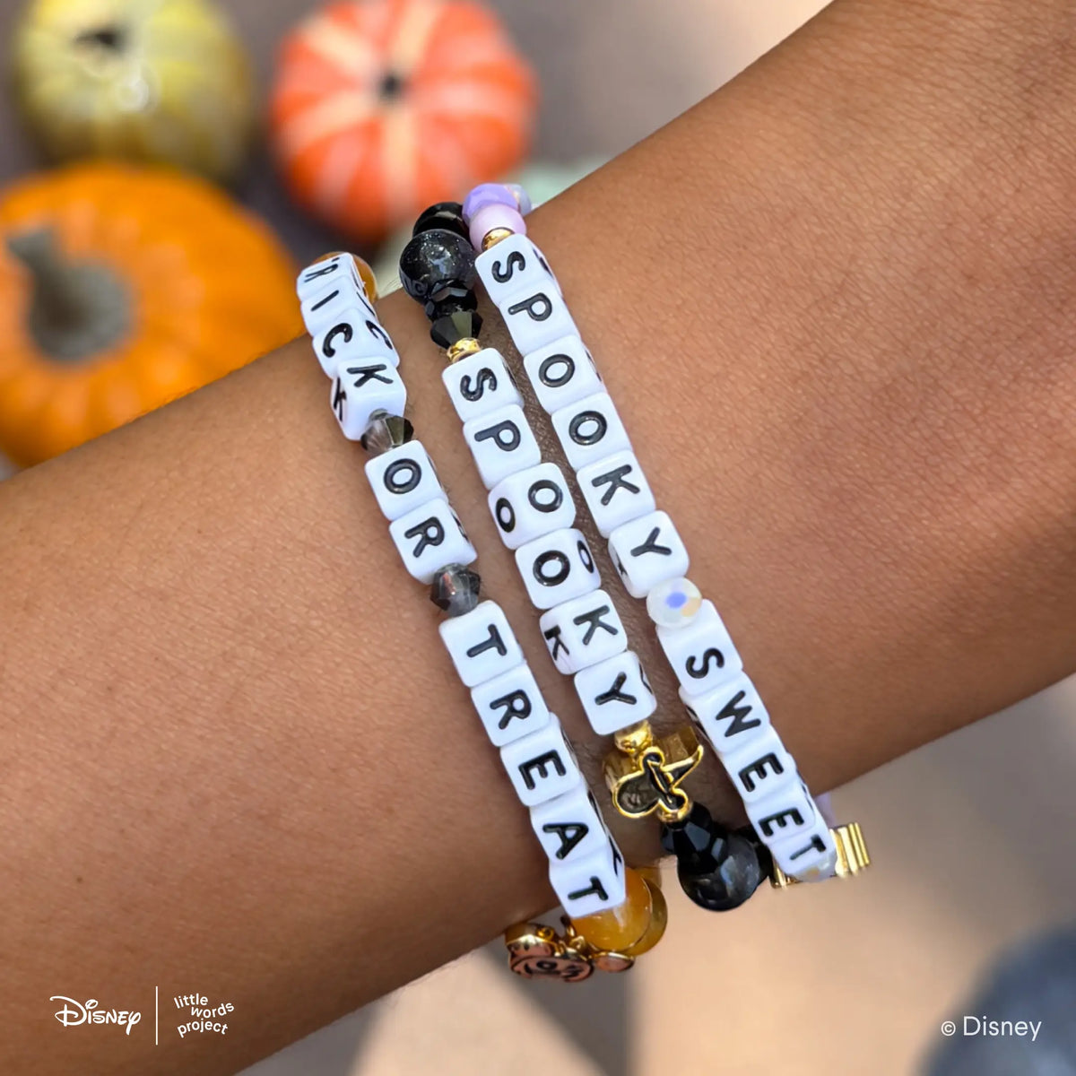 Spooky Disney Mickey & Friends bracelet stacked on-model with the Trick or Treat and Spooky Sweet Disney Halloween bracelets, pumpkins in the background
