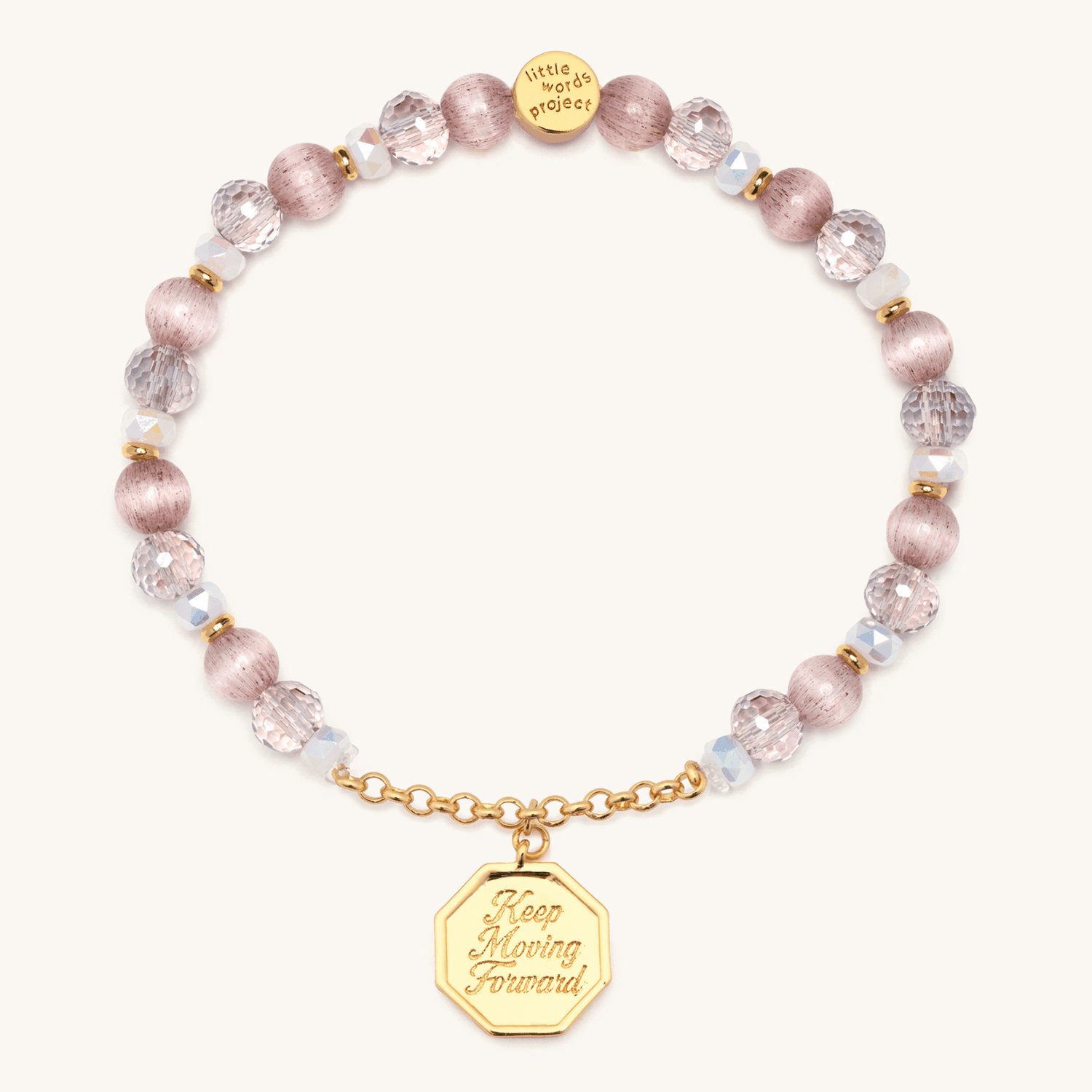 Keep Moving Forward Charm Bracelet animation flipping the octagon gold medallion between the engraved Keep Moving Forward front and the bow and arrow back, pink cat eye and crystal beads, on cream background