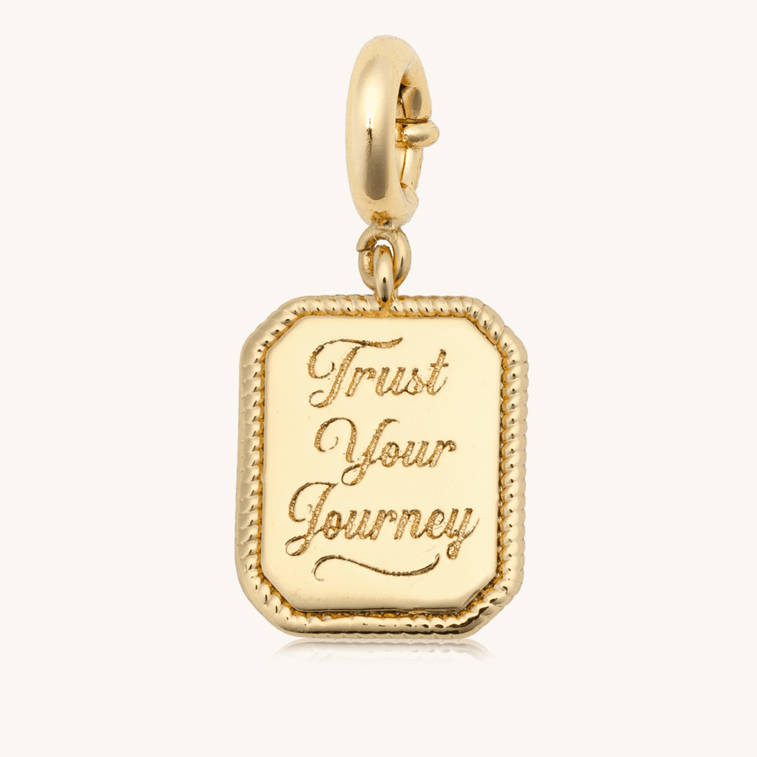 Trust Your Journey Charm animation flipping the 18k gold-plated rectangular medallion between the engraved Trust Your Journey front and the CZ sun over a winding road back, on cream background
