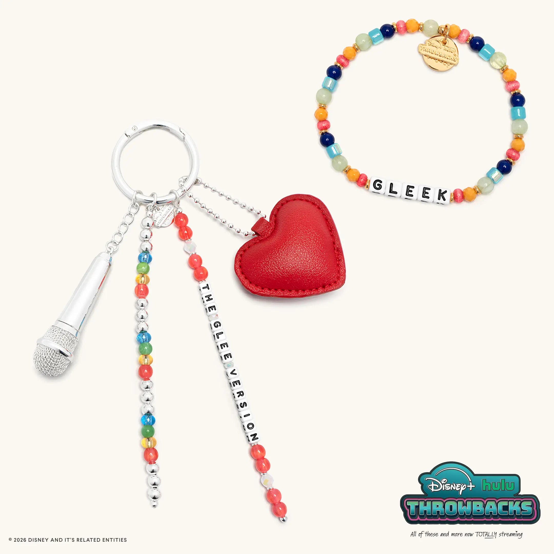 Glee Set from Disney+ Hulu Throwbacks with the Gleek bracelet and The Glee Version bag charm, flat lay on cream
