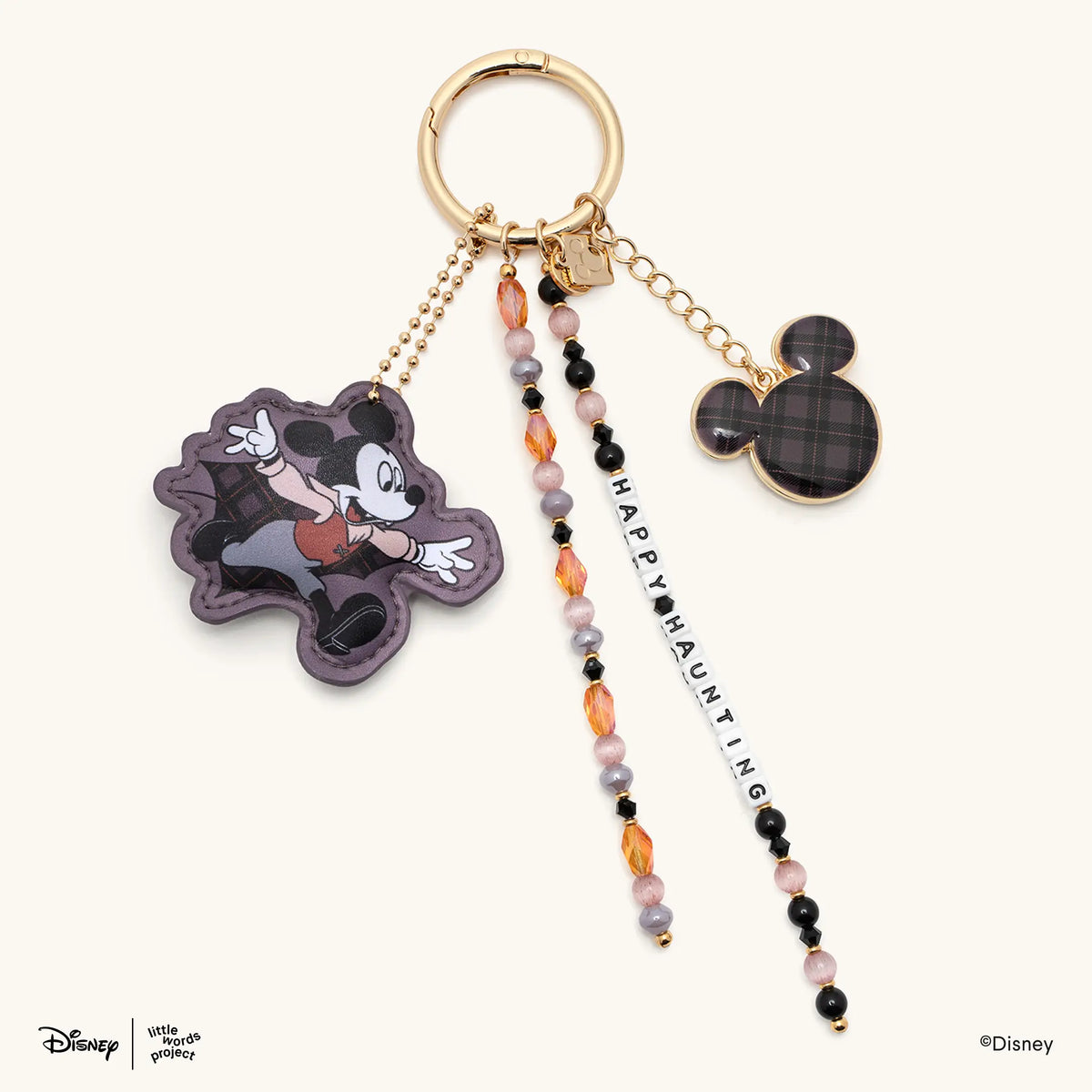 Happy Haunting Disney's Mickey & Friends beaded bag charm with a faux leather vampire Mickey Mouse figure, plaid Mickey Mouse silhouette charm, and orange, pink, and black beaded strands, flat-lay