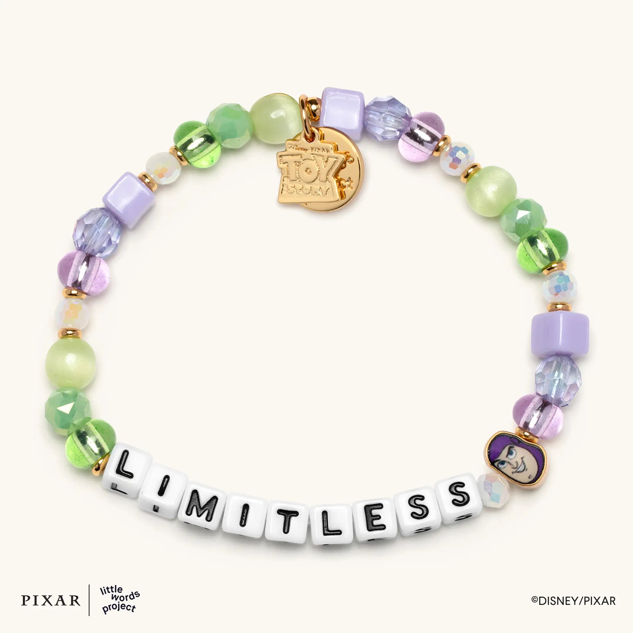 Limitless Toy Story bracelet, green, purple and blue beads spelling LIMITLESS with a gold charm, flat lay