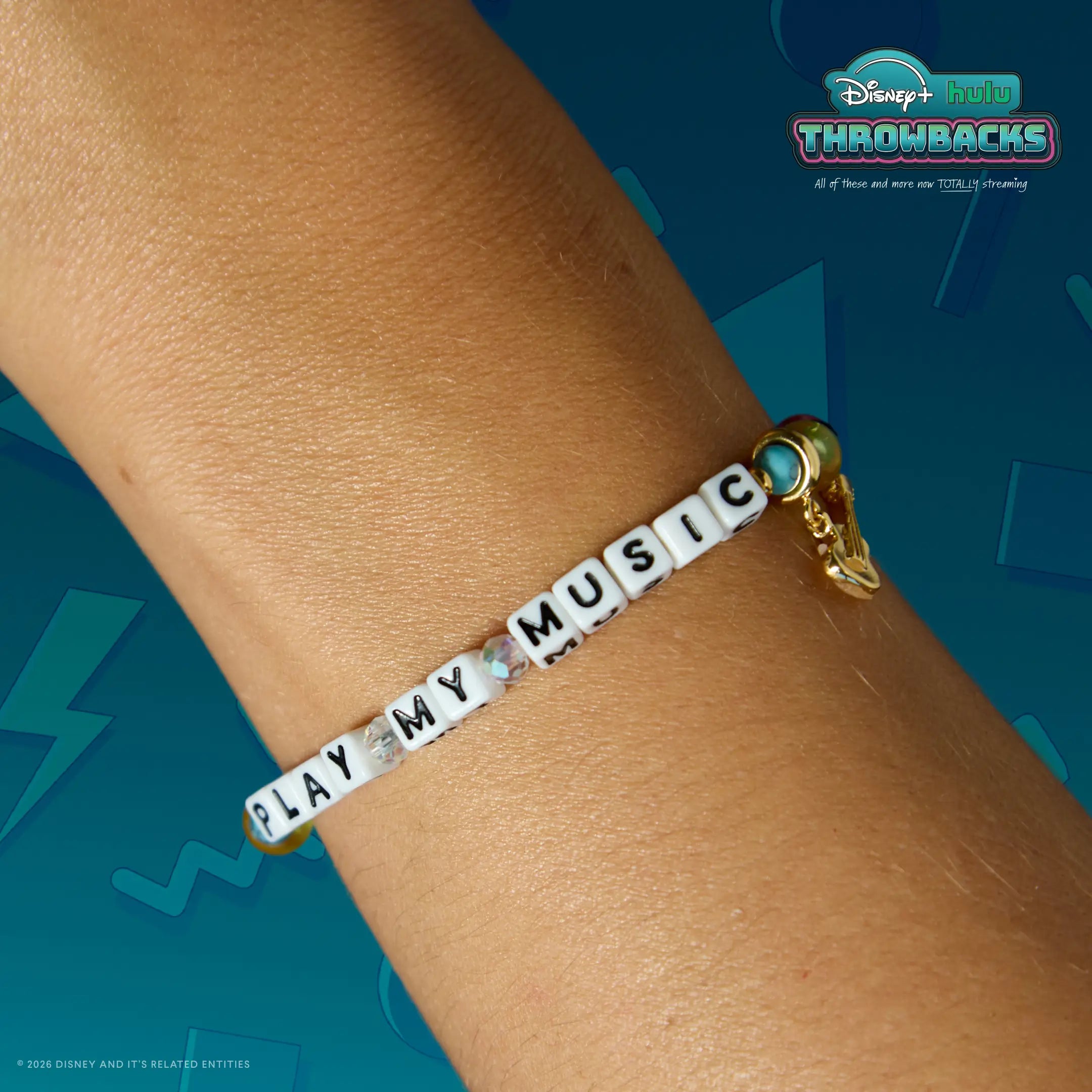 Play My Music Disney+ Hulu Throwbacks bracelet worn on a wrist against a teal Y2K graphic backdrop