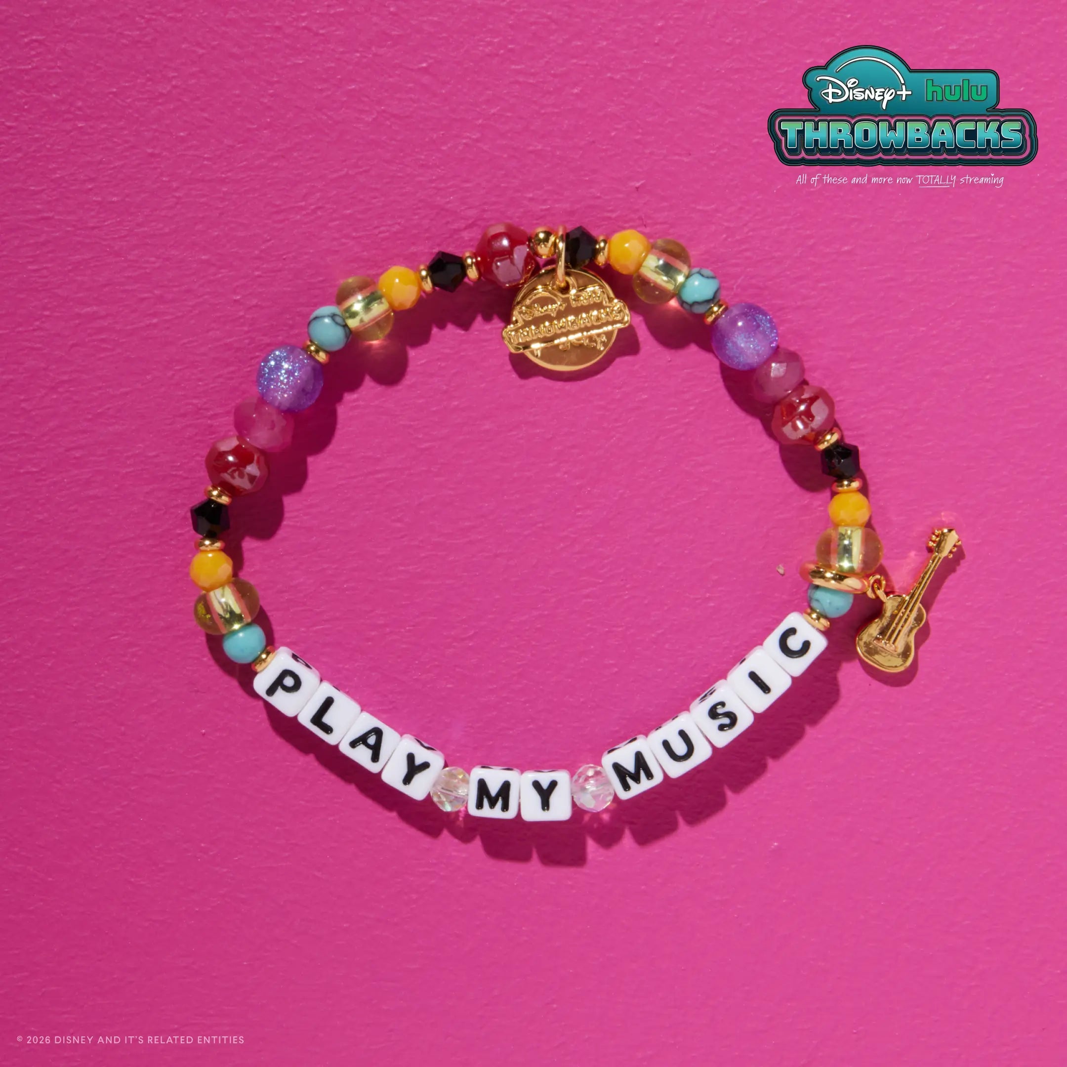 Play My Music Disney+ Hulu Throwbacks bracelet on a hot pink background showing the gold guitar charm and Throwbacks logo tag