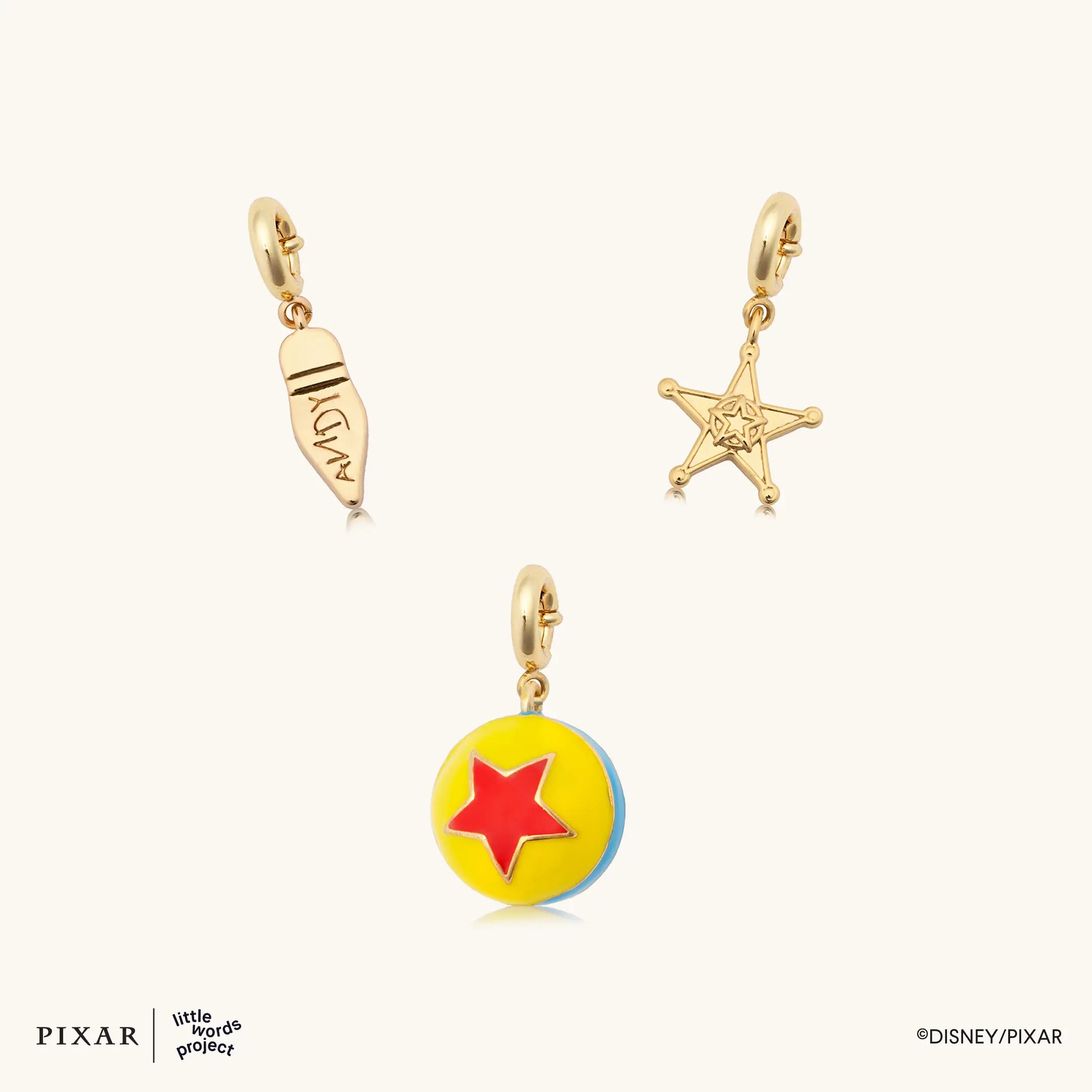 Reach for the Sky Toy Story charm set, gold Woody boot, sheriff badge star and Pixar ball charms, flat lay